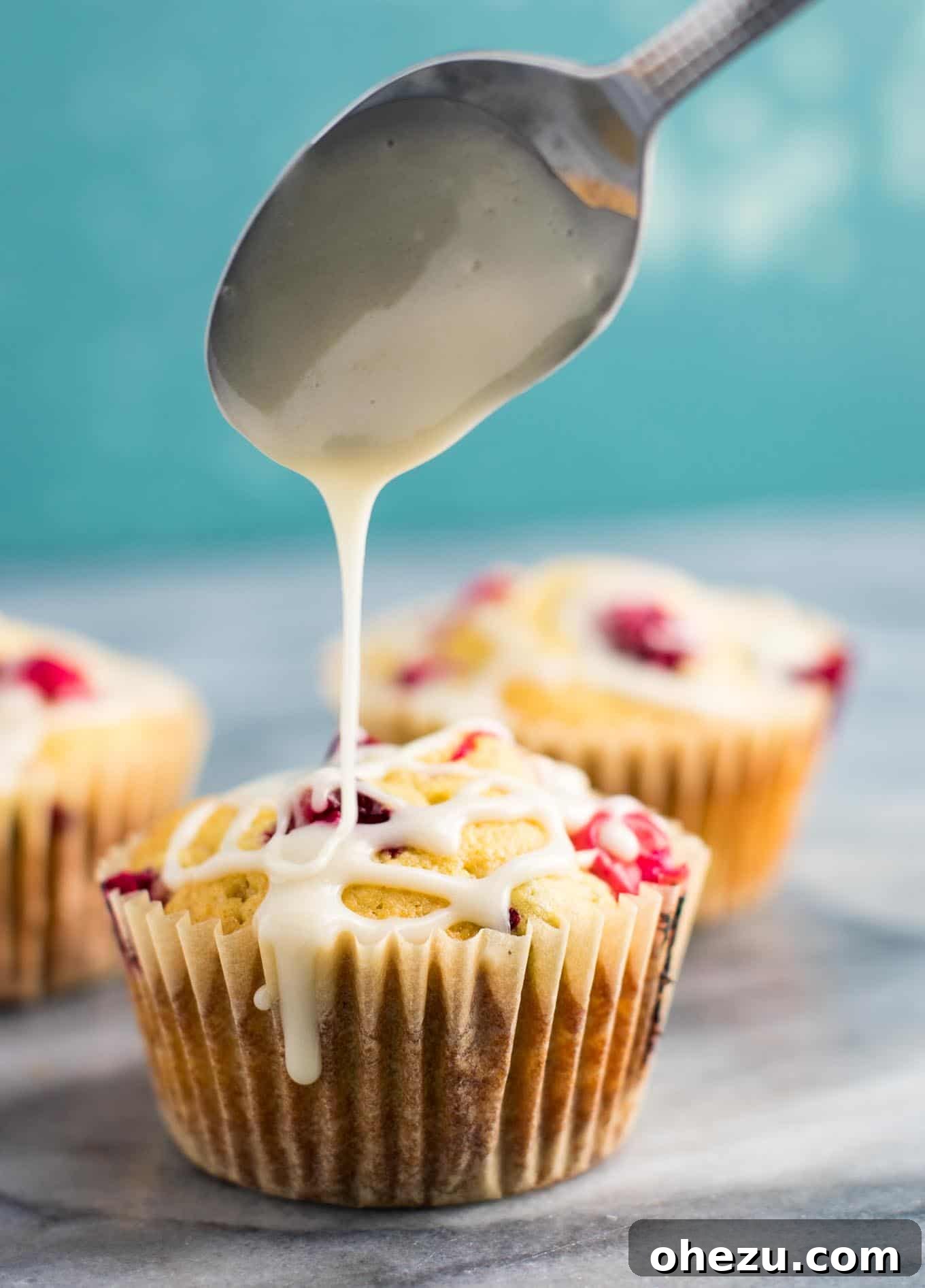 A close-up of a cranberry cream cheese muffin, showing the interior texture and glaze.