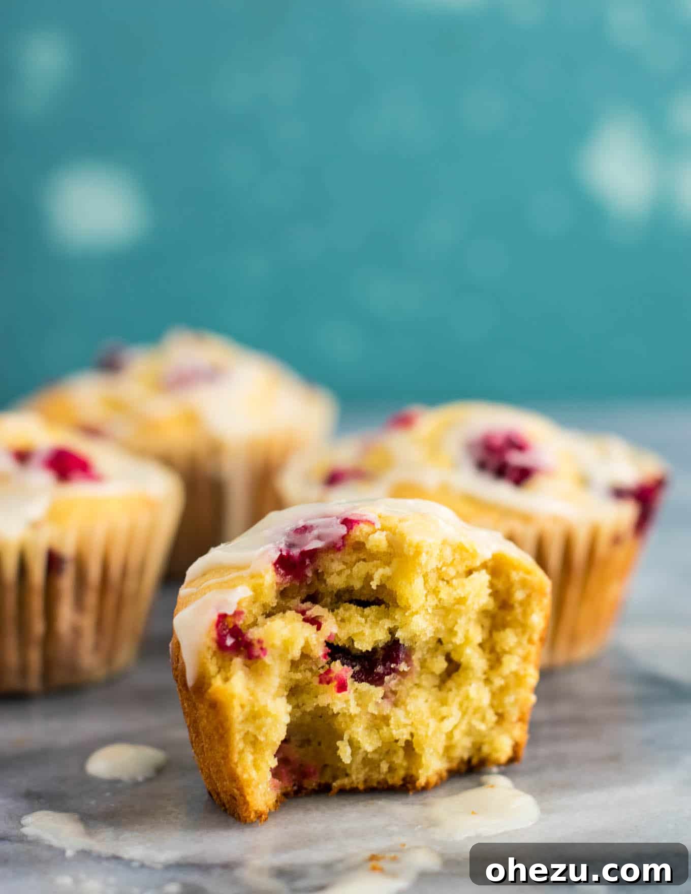 Multiple cranberry cream cheese muffins arranged on a cooling rack, glistening with glaze.