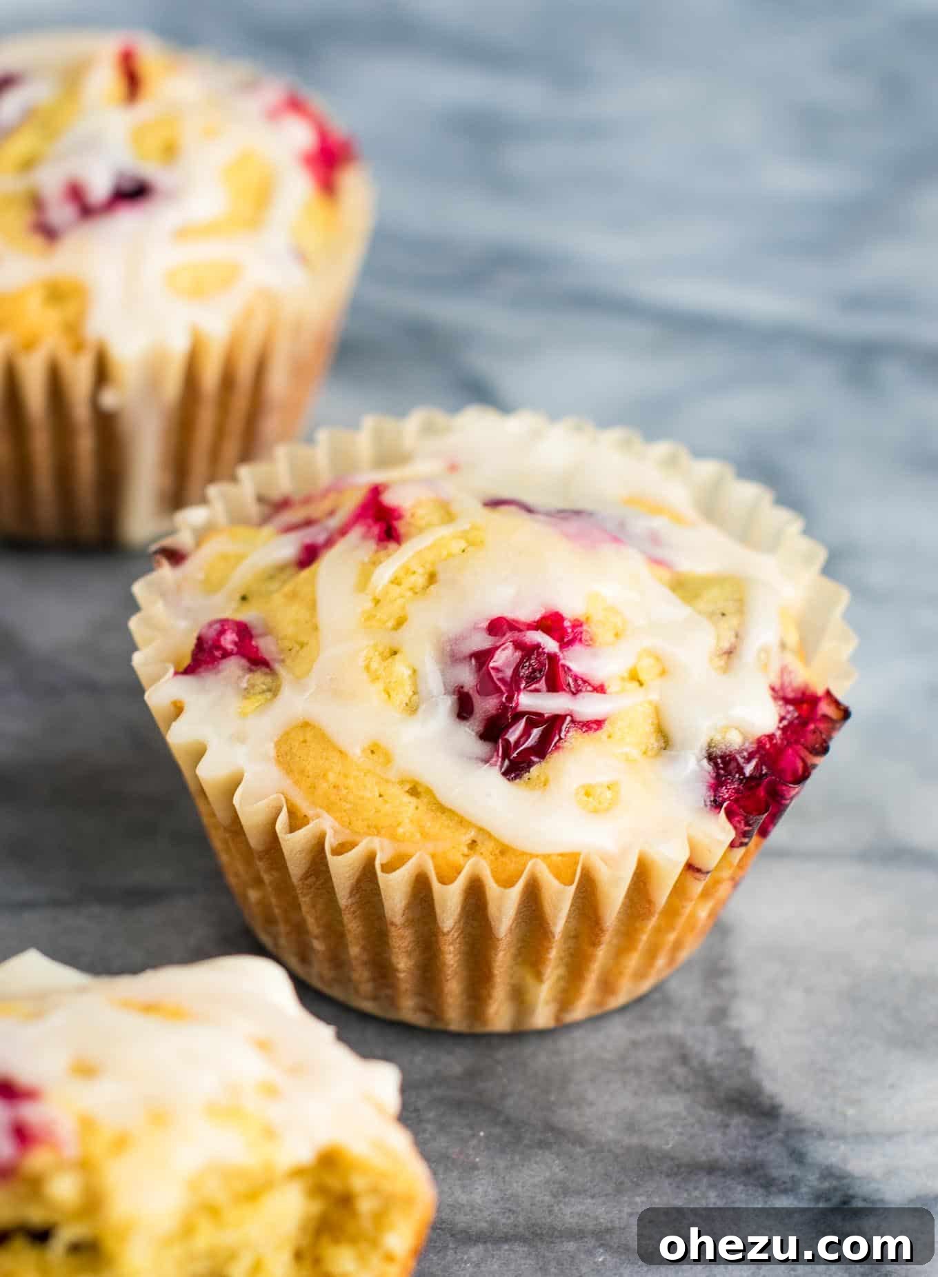 A hand reaching for a cranberry cream cheese muffin from a festive serving plate.