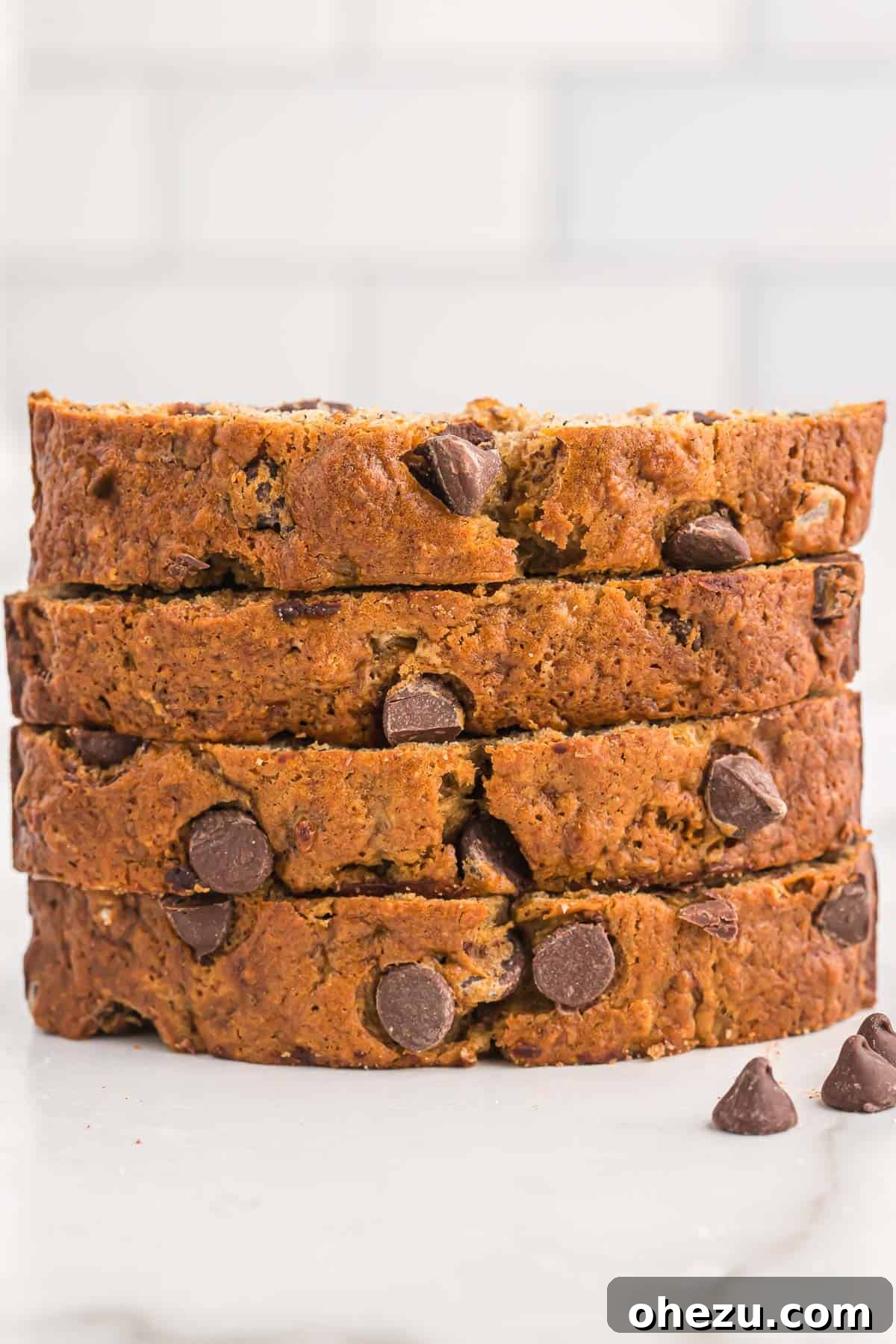 A close-up shot of three beautifully golden-brown slices of chocolate chip banana bread, showcasing their rich texture and abundant, perfectly melted chocolate chips, ready to be enjoyed.