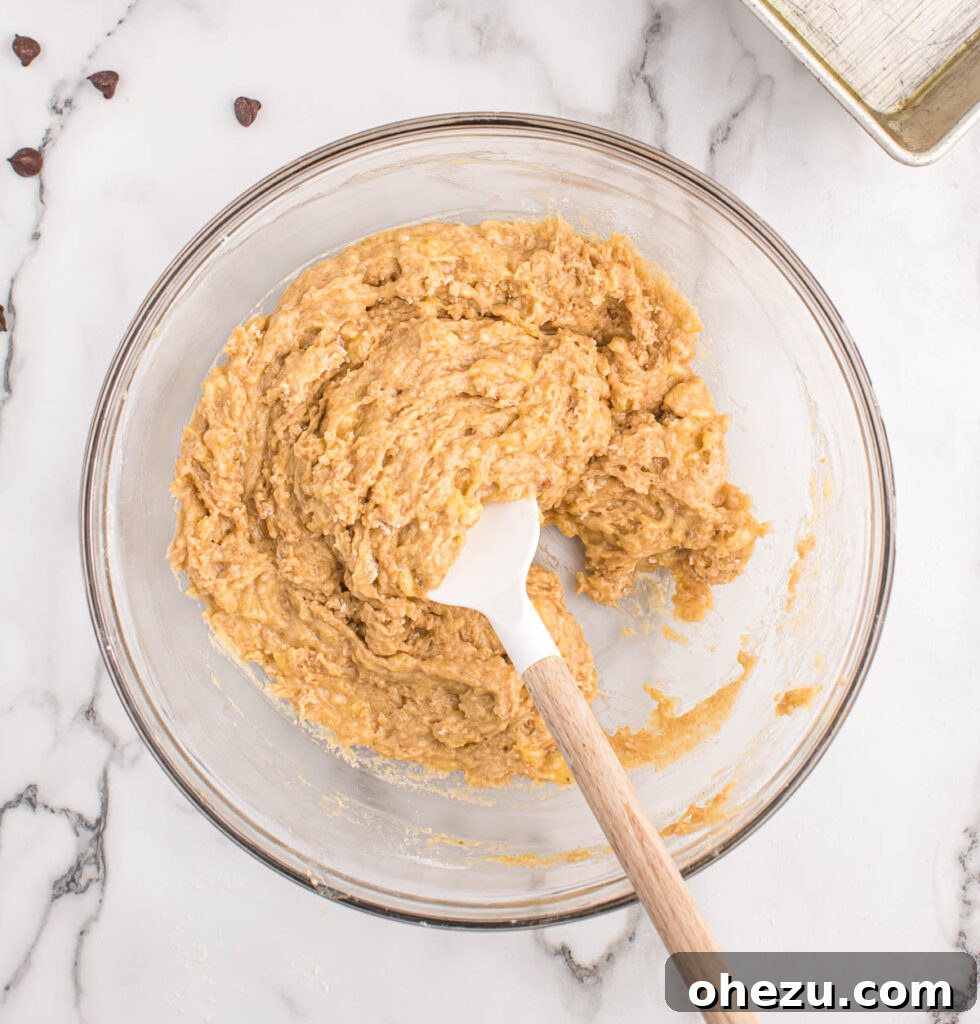 Smooth, creamy chocolate chip banana bread batter resting in a large mixing bowl, perfectly prepared and ready for the final addition of chocolate chips.