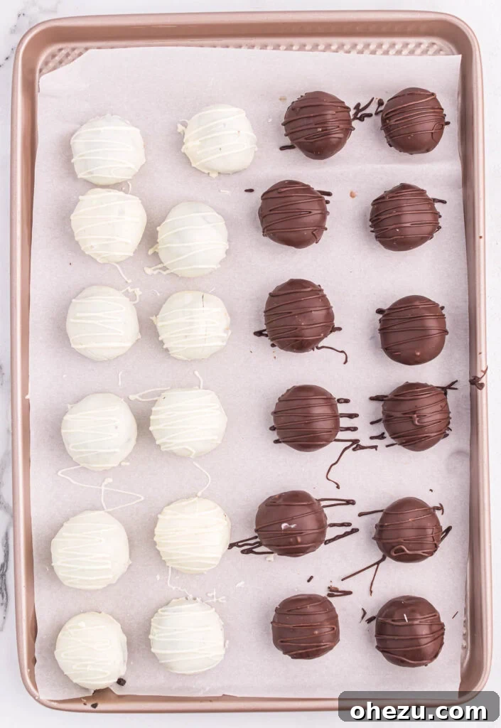 Emerald Oreo Delights 11 A full baking sheet showcasing an array of finished white and dark chocolate Mint Oreo truffles, each with an elegant opposing chocolate drizzle.