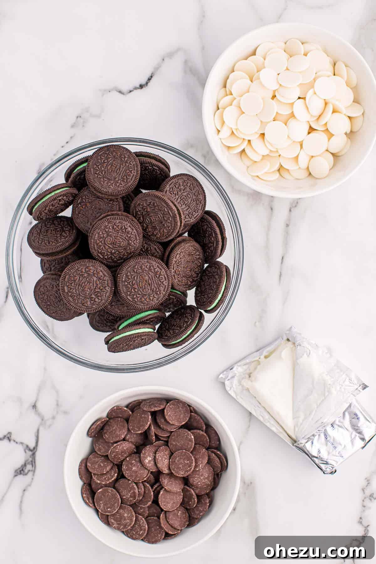Emerald Oreo Delights 3 Four simple ingredients laid out: a package of Mint Oreos, a block of softened cream cheese, white vanilla melting wafers, and dark chocolate melting wafers, ready to be transformed into delicious truffles.