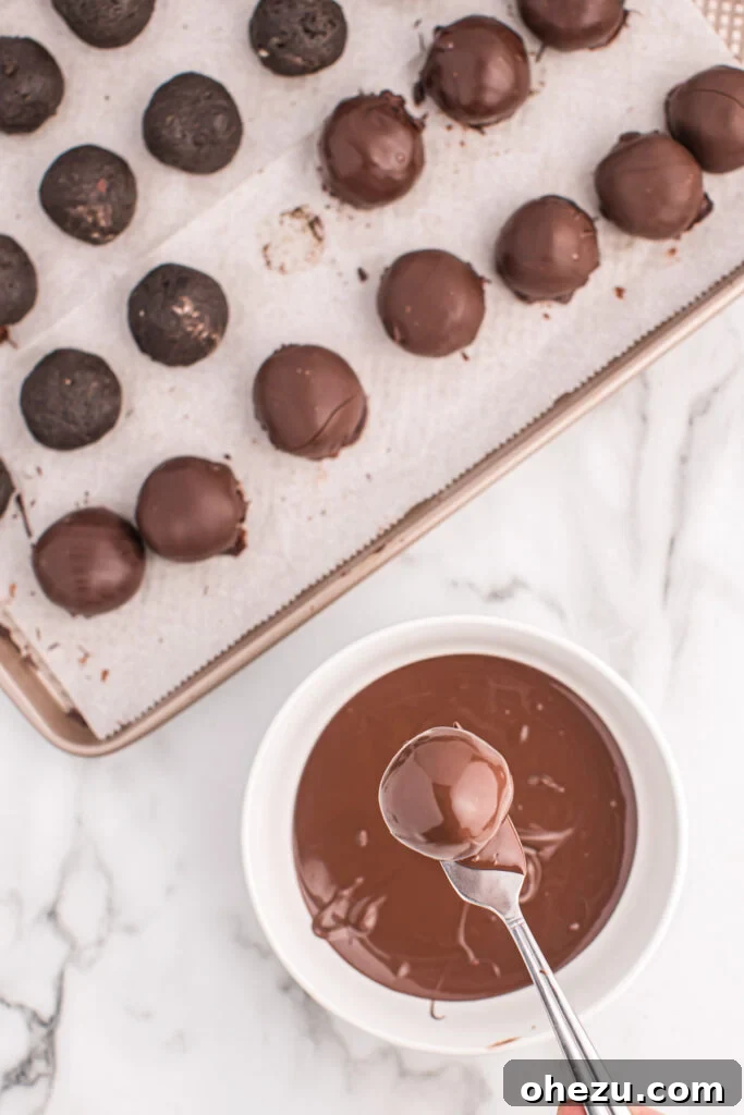 Emerald Oreo Delights 8 A Mint Oreo ball being carefully dipped into a bowl of melted dark chocolate, ensuring a full and even coating.