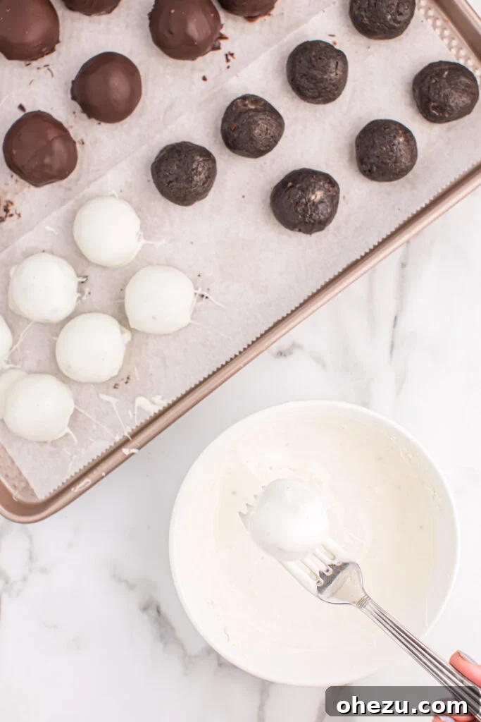 Emerald Oreo Delights 9 A Mint Oreo ball being dipped into a bowl of smooth, melted white vanilla chocolate, contrasting with the dark chocolate process.
