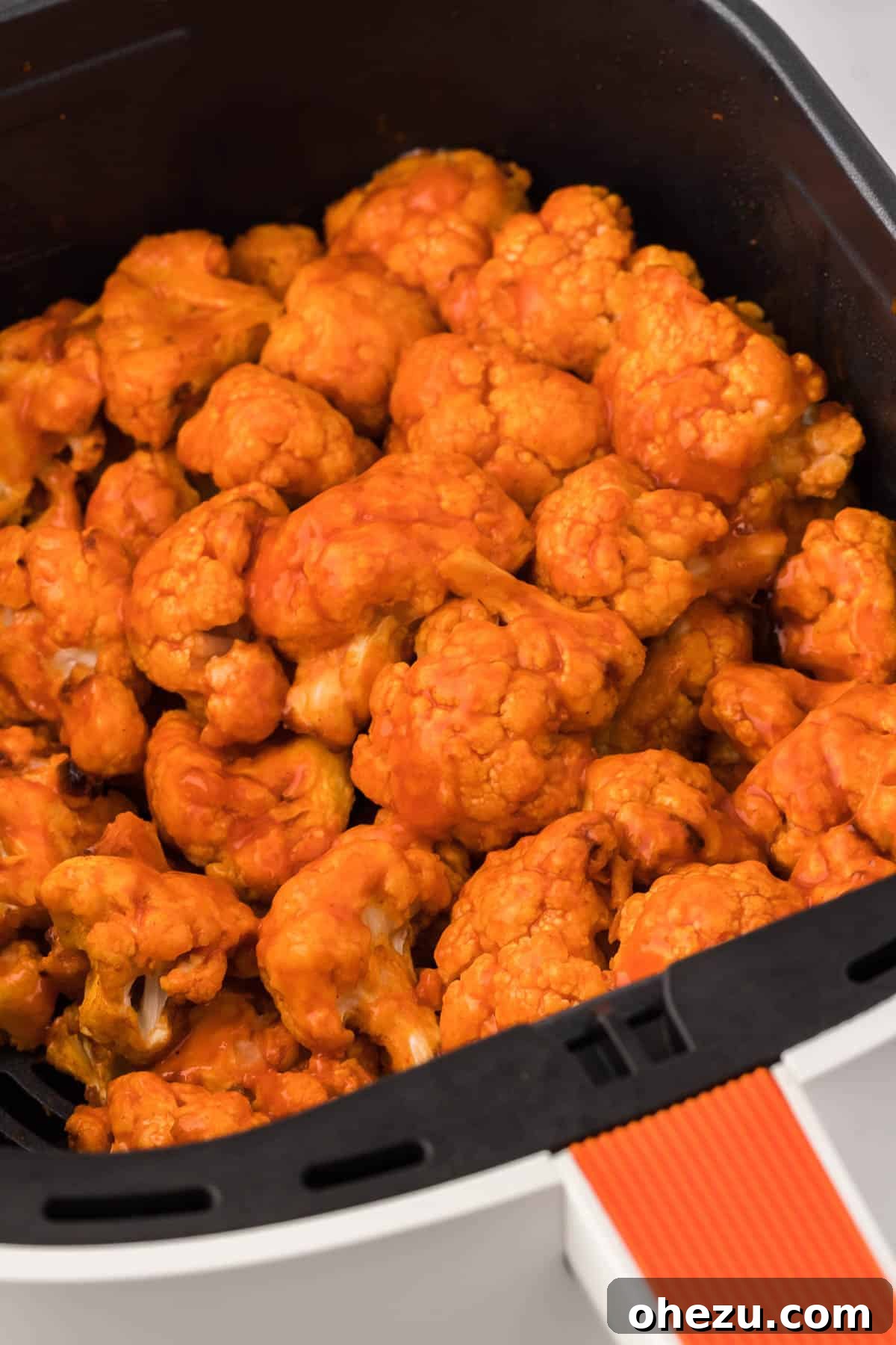 A basket full of perfectly golden and crispy air fryer buffalo cauliflower bites, ready for serving.