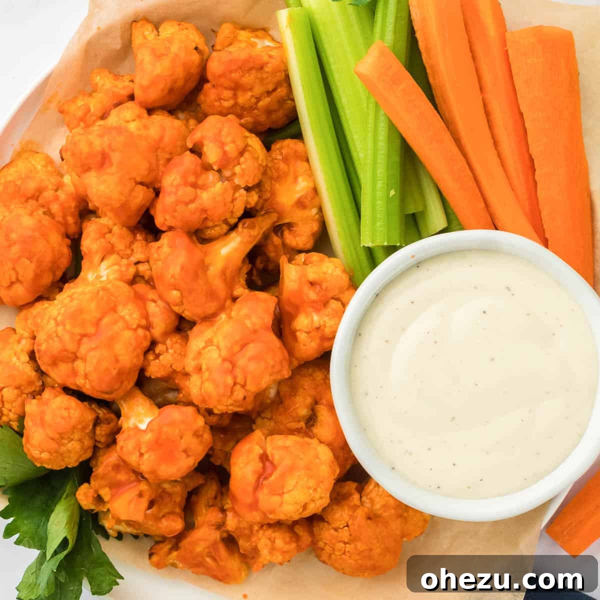 A final, beautifully styled shot of air fryer buffalo cauliflower bites on a serving platter, accompanied by celery, carrots, and ranch dressing.