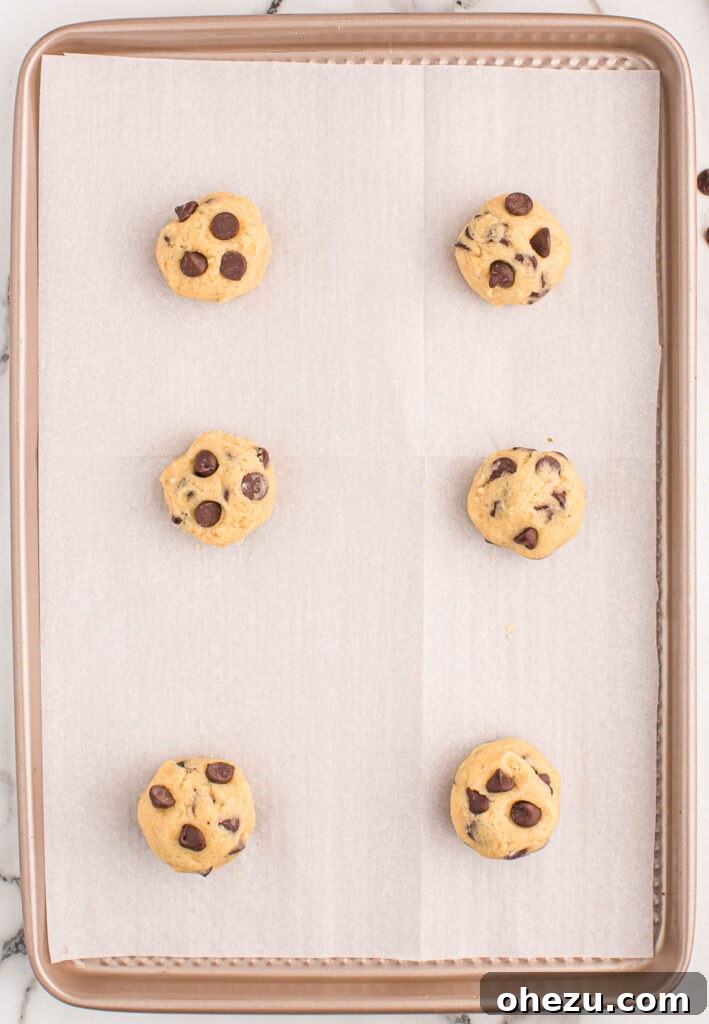 Perfect Chocolate Chip Cookies With No Brown Sugar 16 Unbaked chocolate chip cookie dough portions evenly spaced on a parchment-lined baking sheet