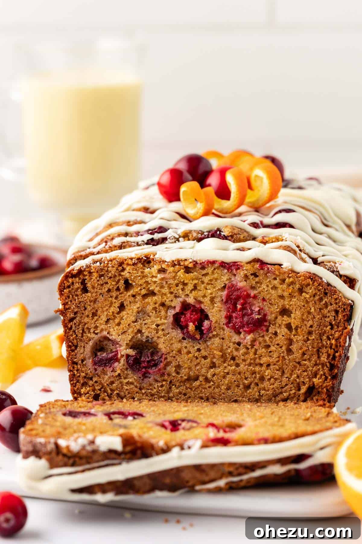 Close-up of a slice of white chocolate glazed cranberry eggnog bread, showing cranberries and moist texture.