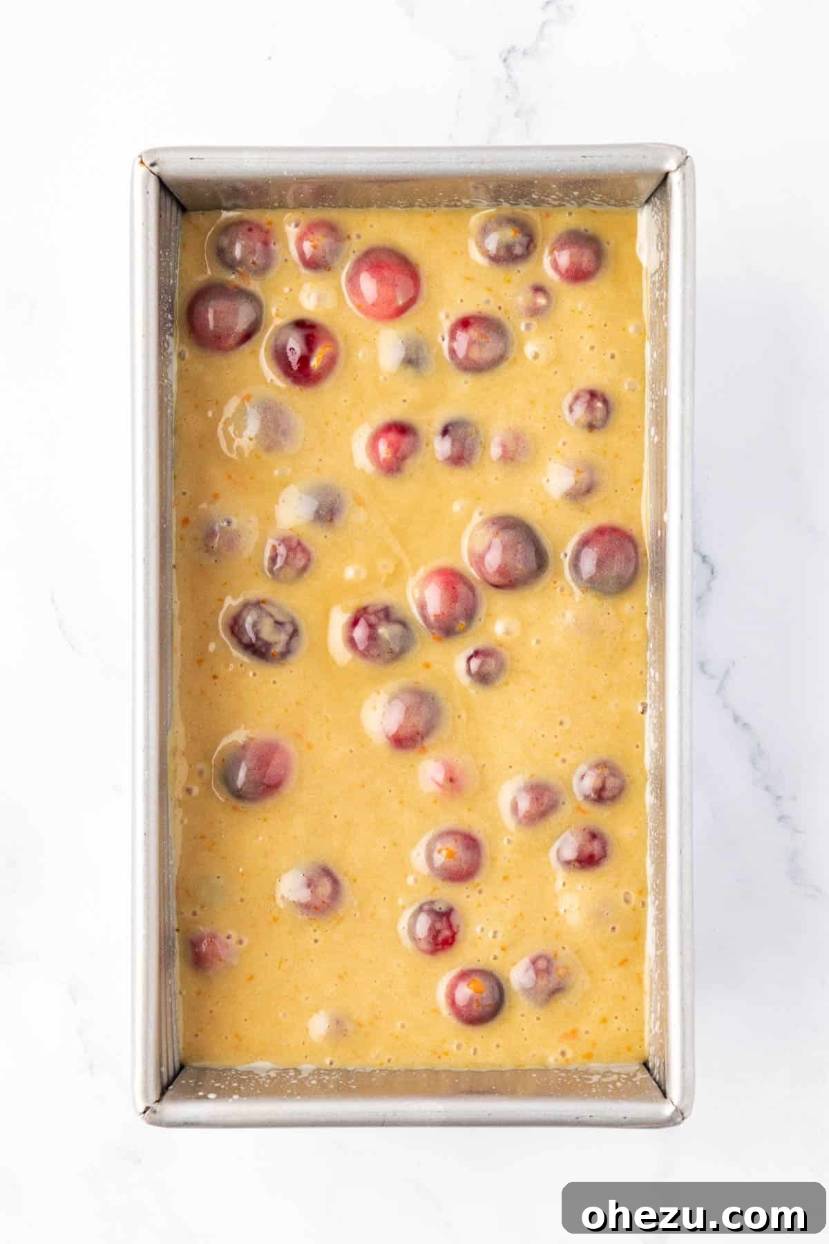 Cranberry eggnog bread batter poured into a greased loaf pan.