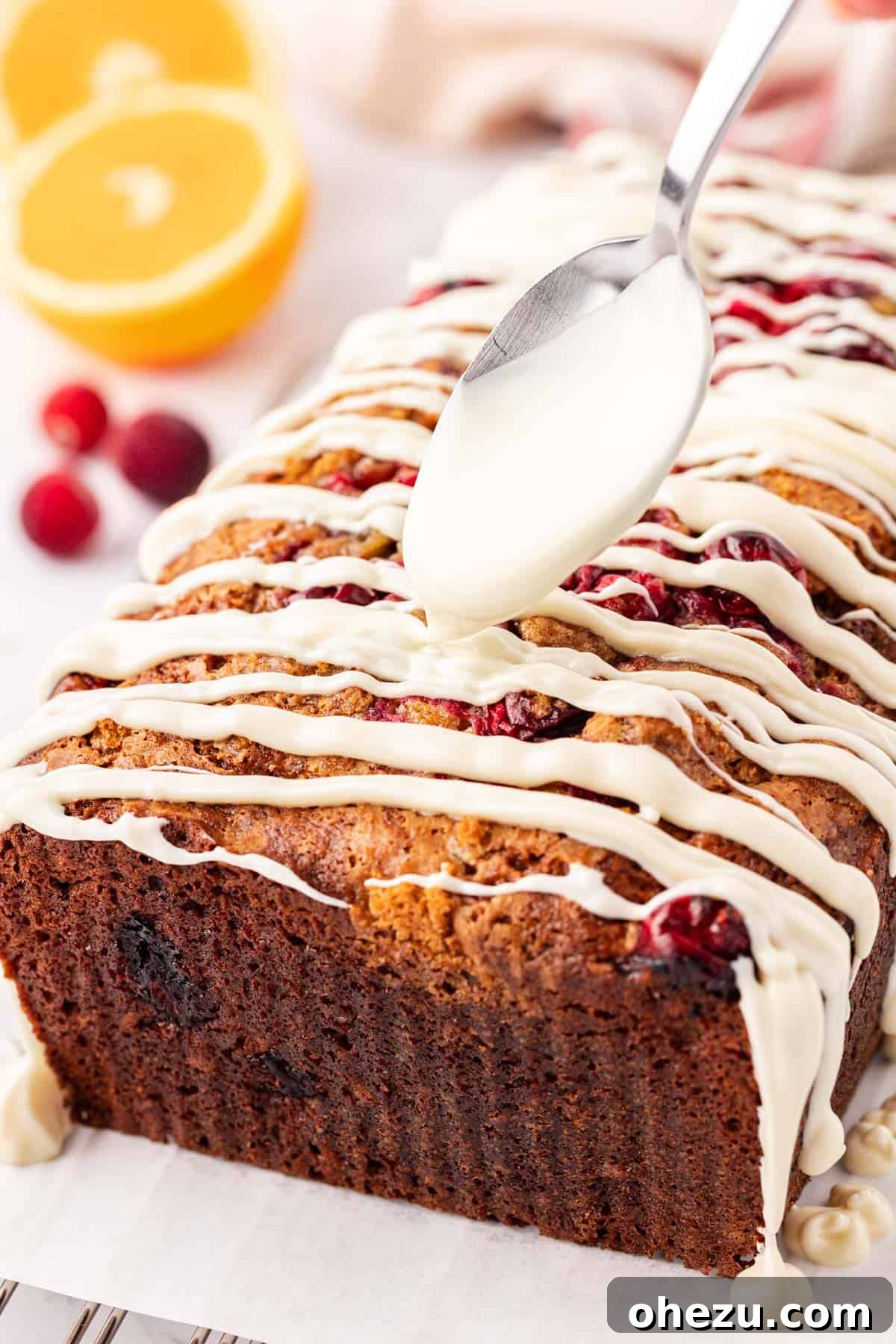 A beautifully glazed cranberry eggnog bread on a cooling rack, glistening with white chocolate.