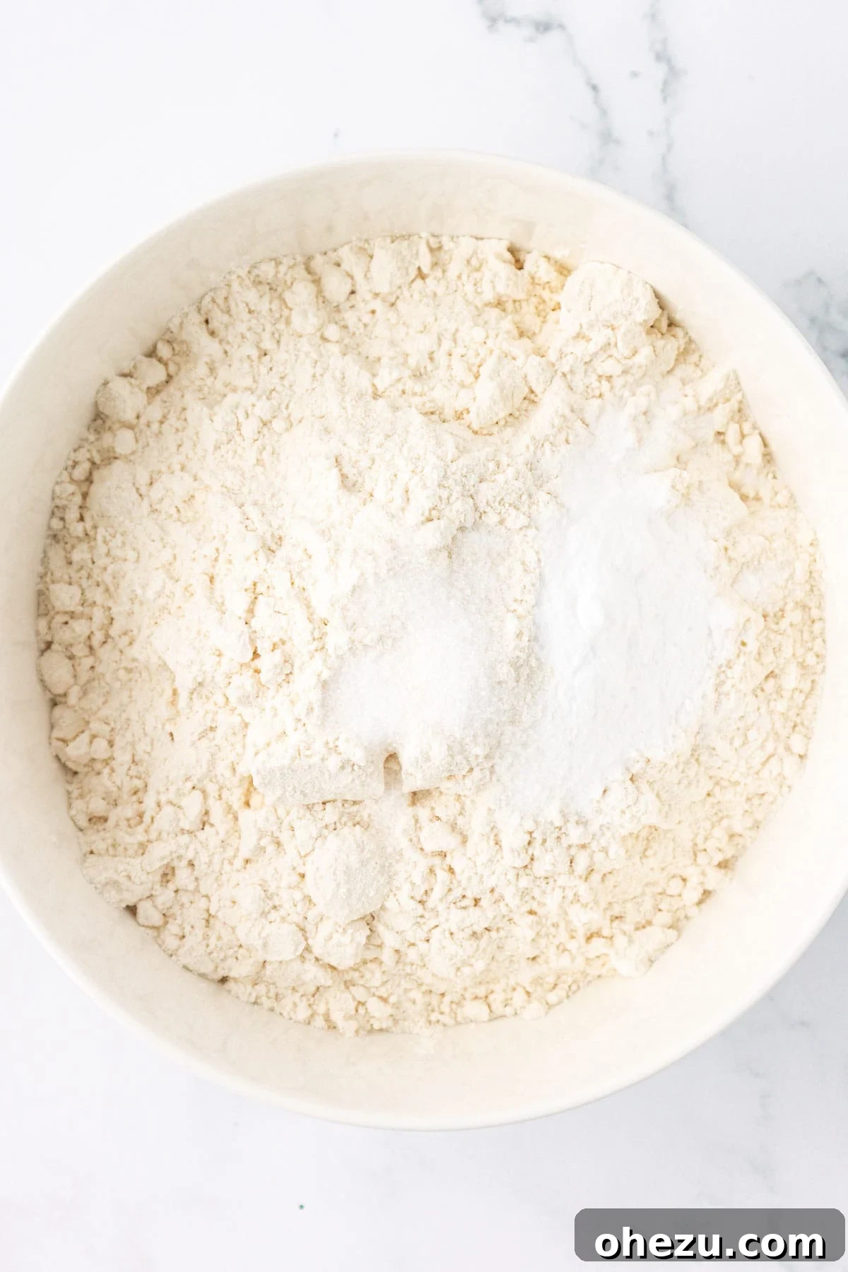 Dry ingredients including flour, baking soda, and salt, in a mixing bowl before whisking.