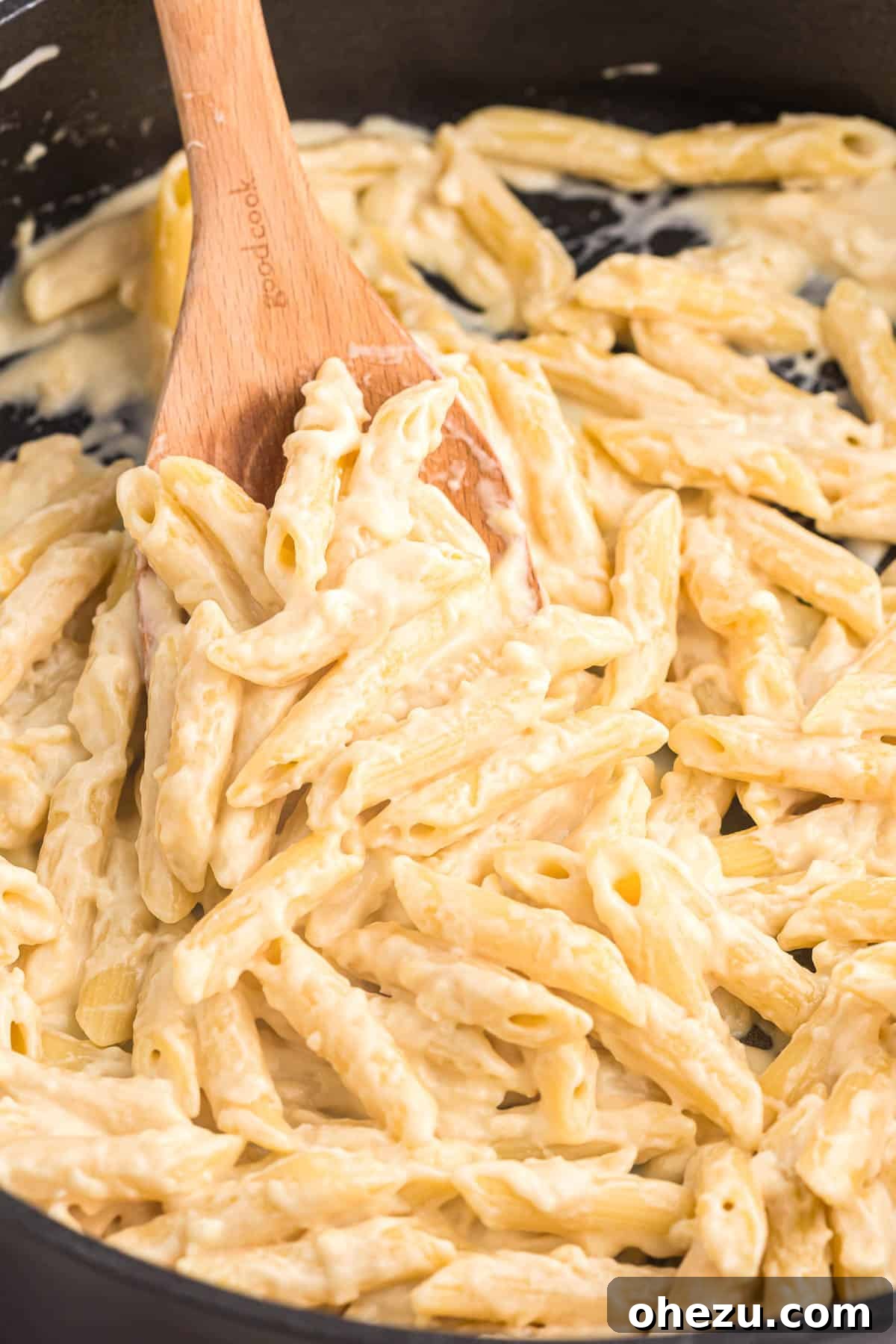 creamy penne pasta on a wooden spoon