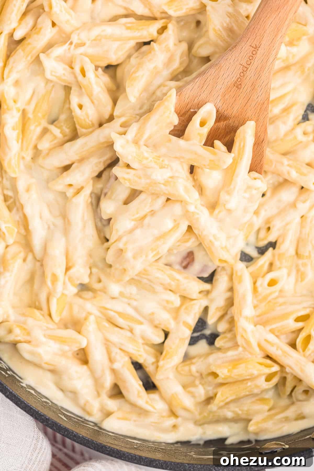 creamy penne pasta on a wooden spoon