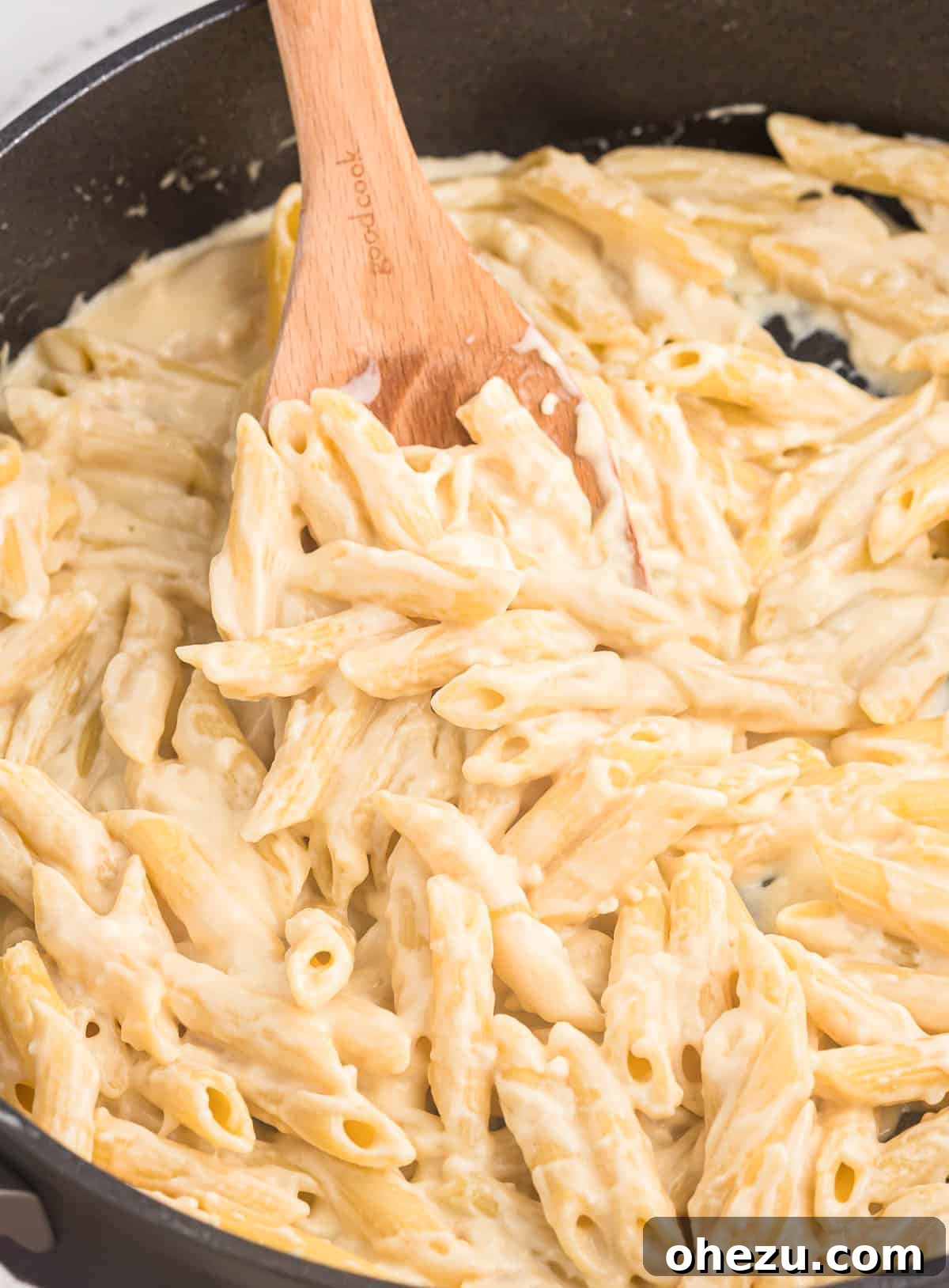 creamy penne pasta on a wooden spoon