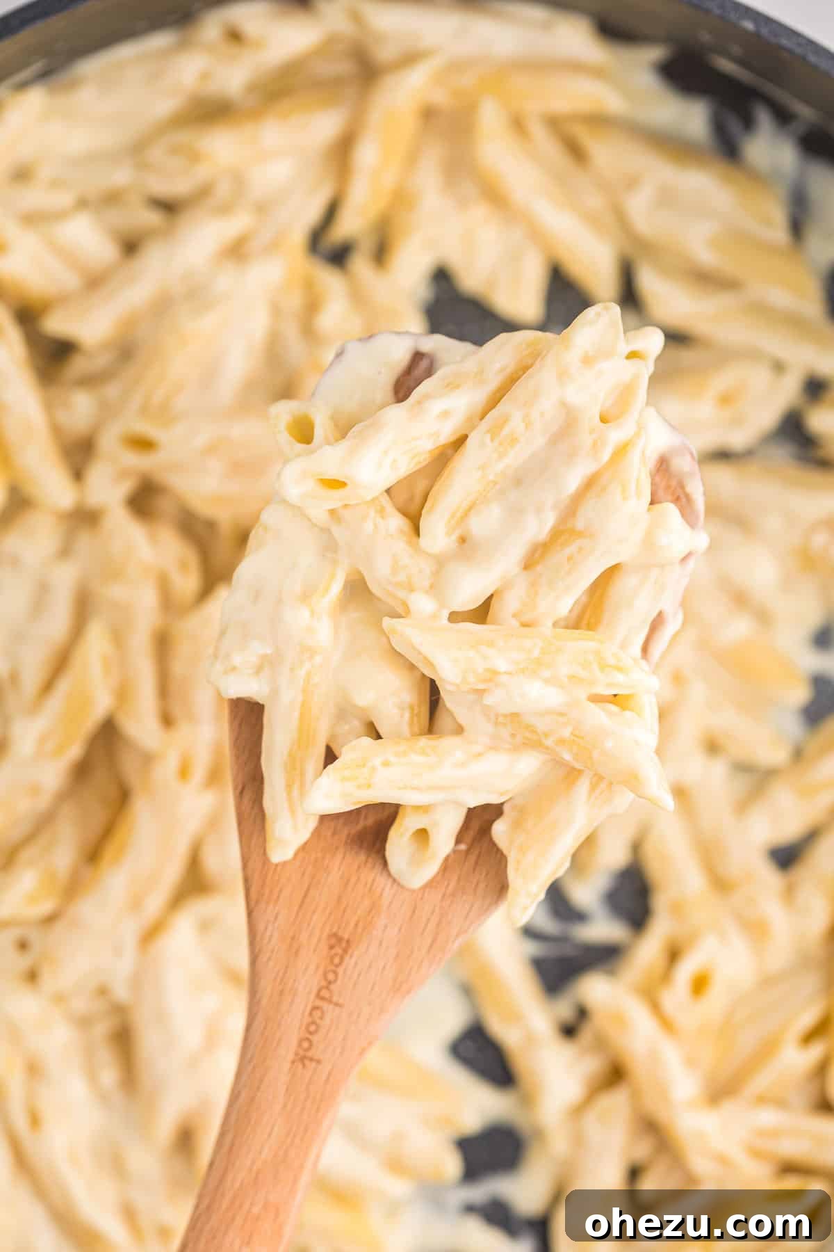 creamy penne pasta on a wooden spoon