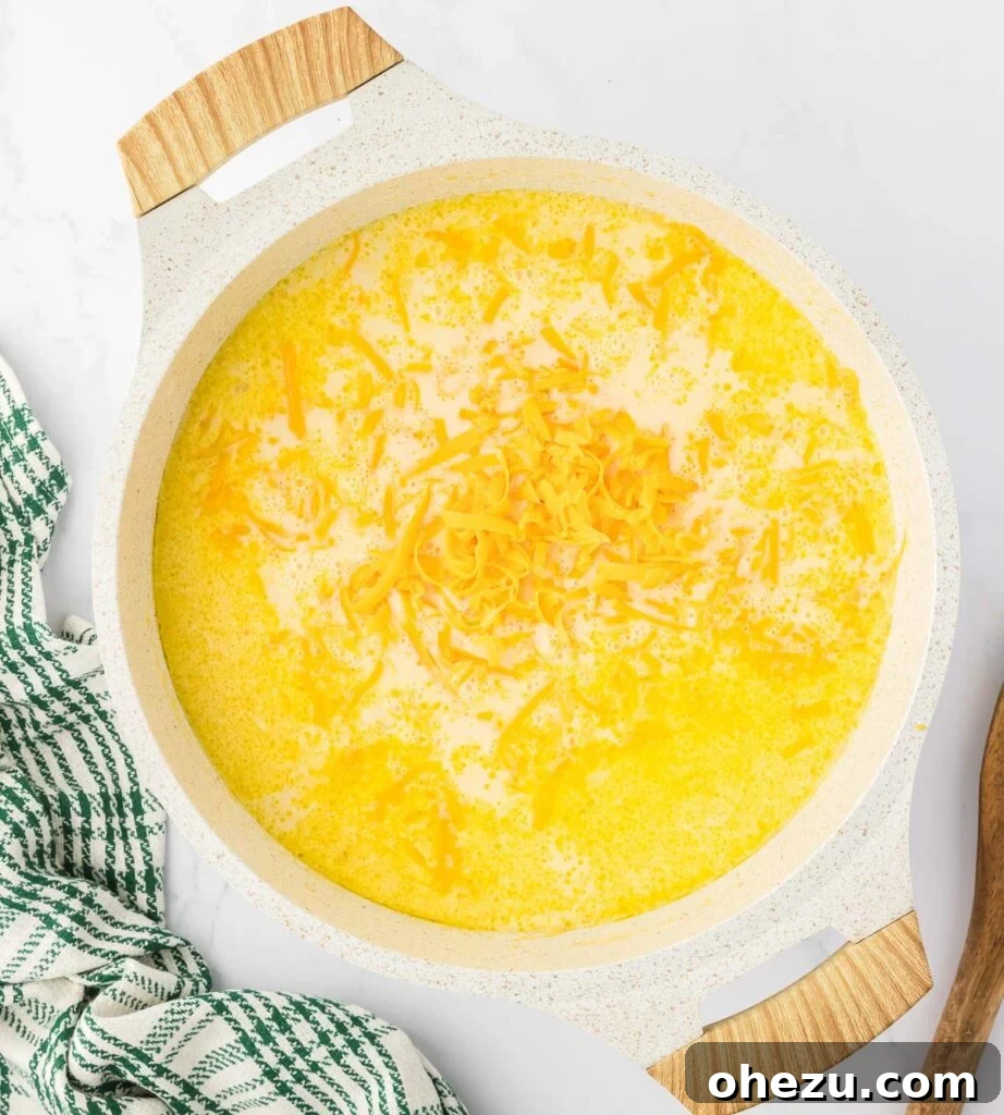 Velvety Potato Warmth 15 Freshly grated cheddar cheese being gently stirred into the hot potato soup, melting into a smooth consistency.