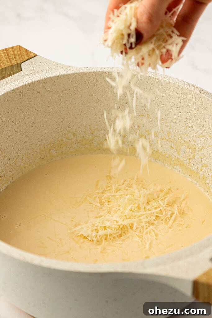 Farfalle Flair 11 Adding freshly grated parmesan cheese to the thickened cream sauce.