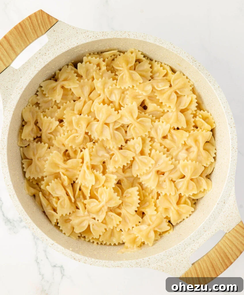 Farfalle Flair 12 Creamy bow tie noodles simmering in a pan, fully coated in sauce.