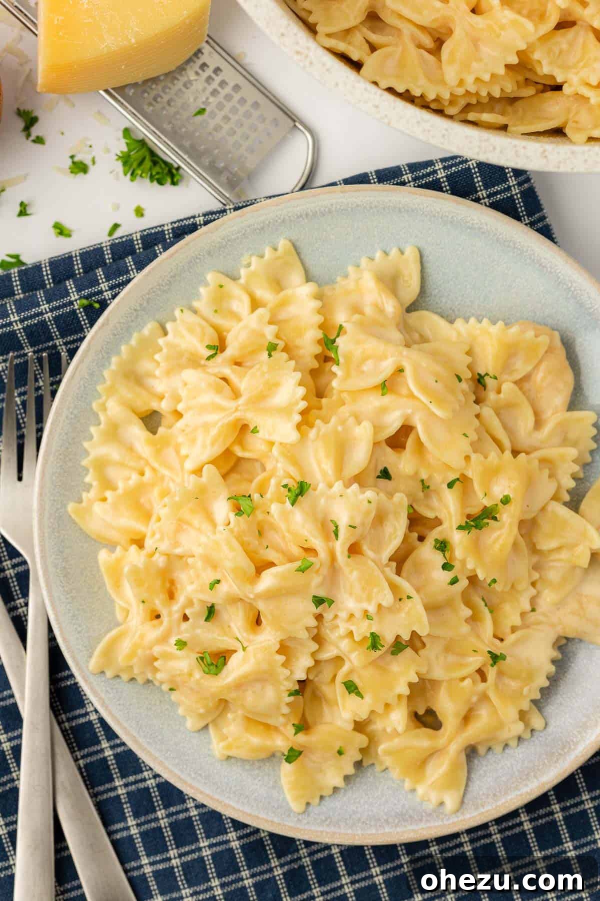 Farfalle Flair 16 Another appealing shot of creamy bow tie pasta served on a white plate with fresh garnish.