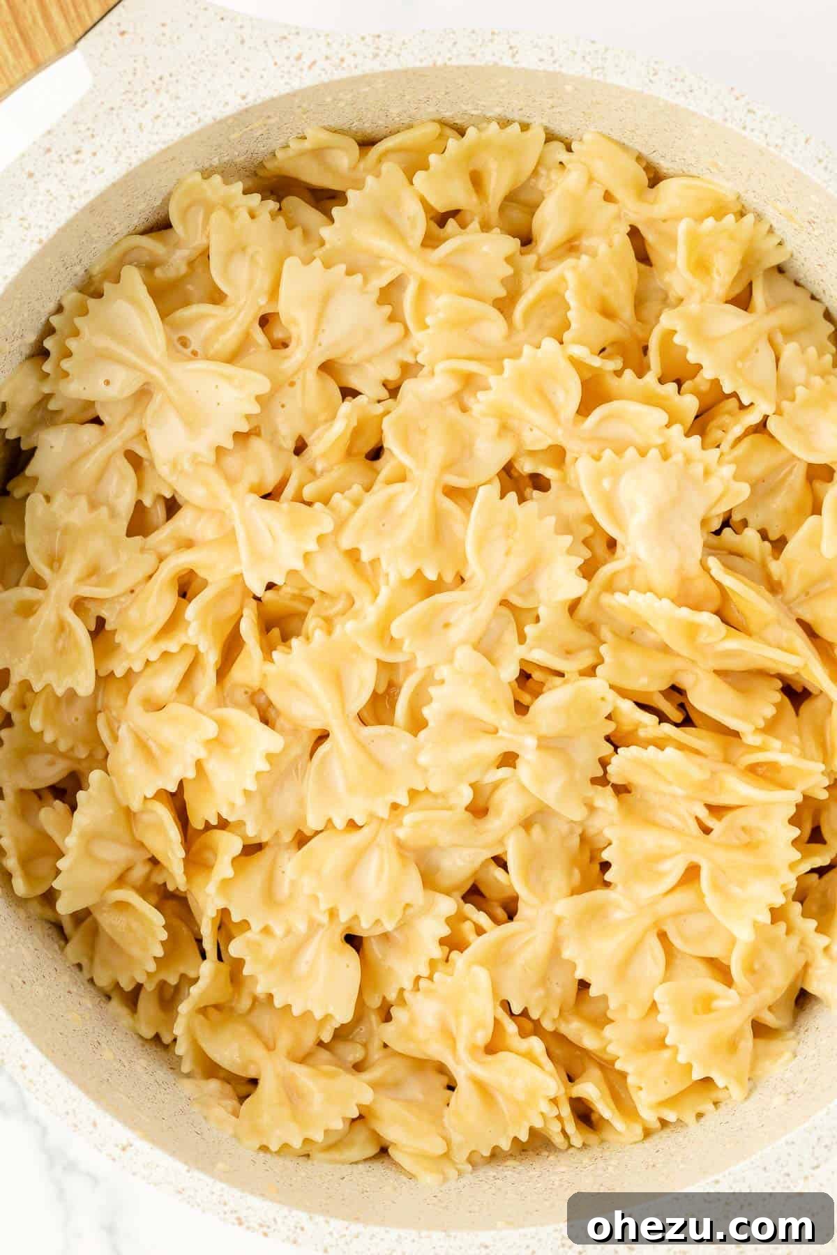 Farfalle Flair 3 Close-up shot of cooked bow tie pasta glistening with creamy sauce.