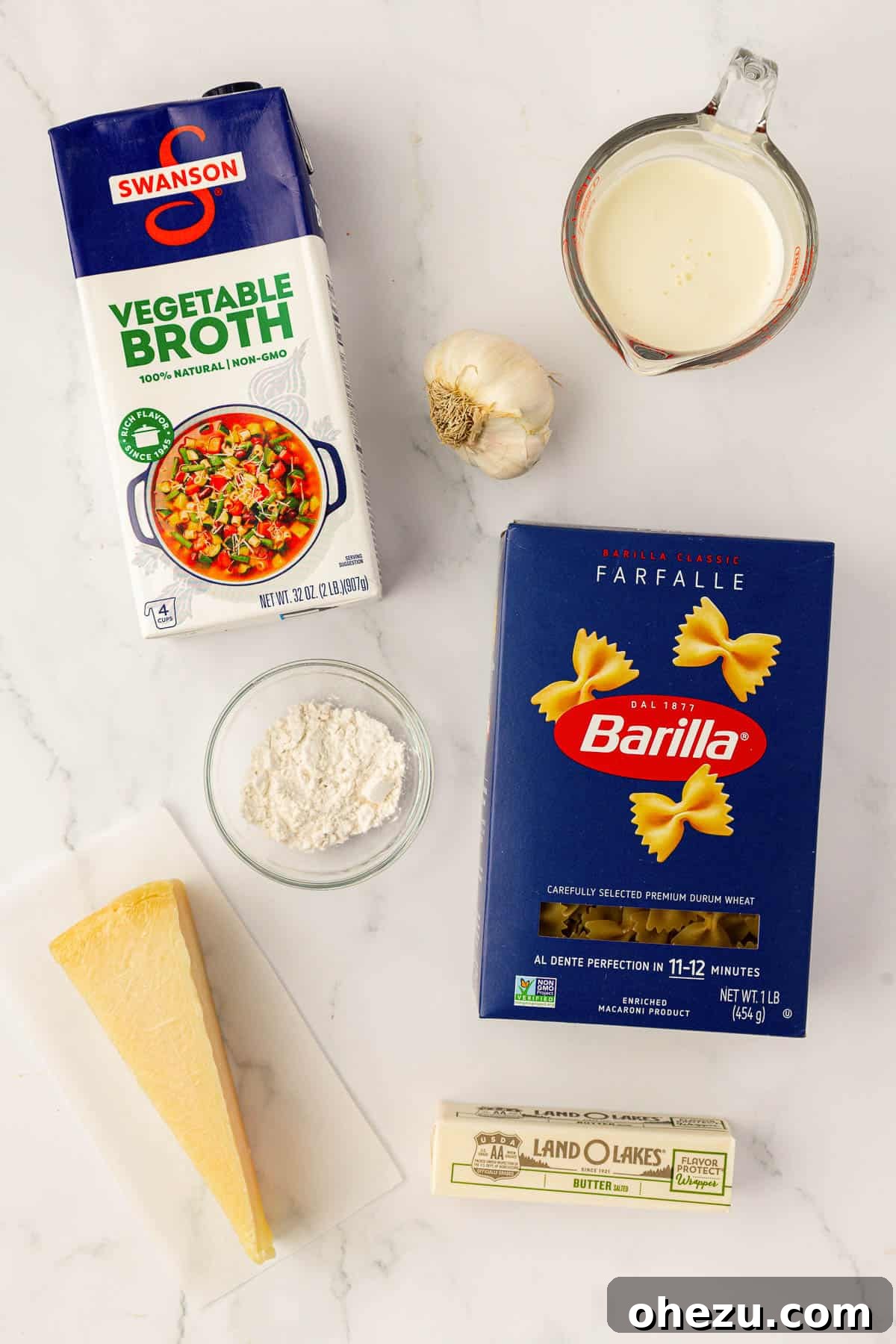 Farfalle Flair 4 A flat lay of fresh ingredients including bow tie pasta, cream, broth, parmesan, butter, flour, and garlic.