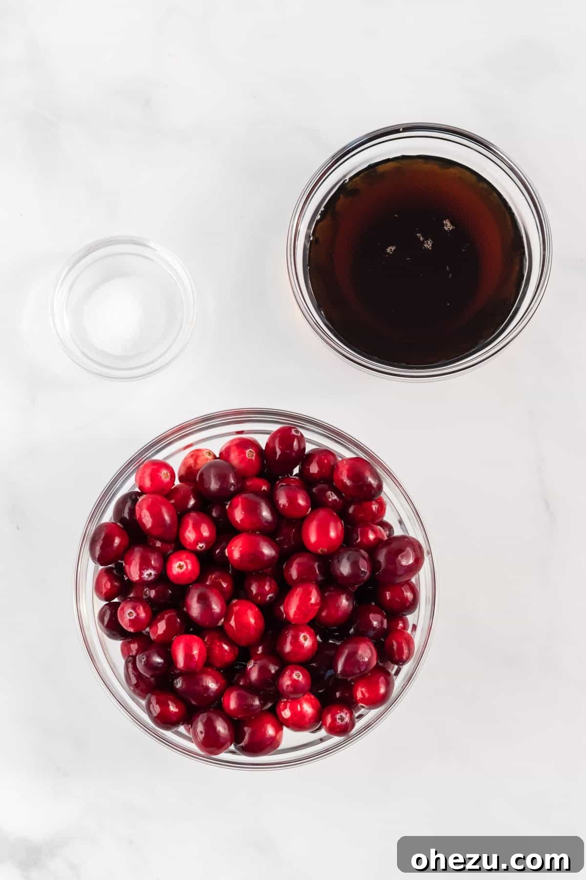 Crafted Cranberry Bliss 3 Three small bowls displaying the key ingredients for homemade cranberry sauce: fresh cranberries, pure maple syrup, and a pinch of salt.
