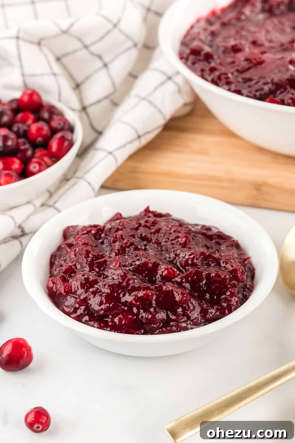 Crafted Cranberry Bliss 7 A festive white bowl brimming with fresh, homemade cranberry sauce, garnished with a few whole cranberries and rosemary sprigs for a holiday touch.