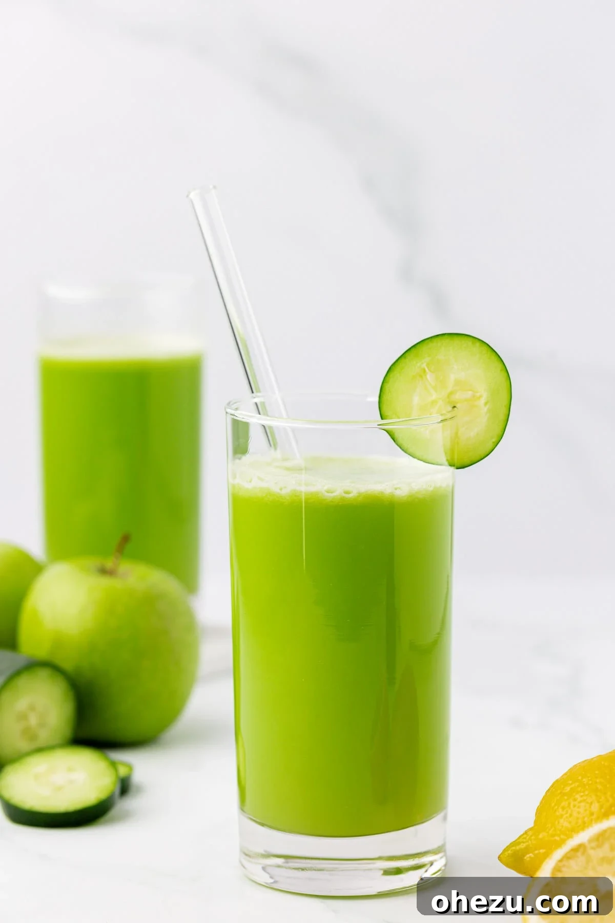 A glass of vibrant green cucumber juice with a cucumber slice on the rim, showcasing its freshness and appeal.