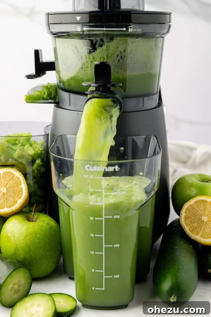Close-up shot of vibrant green cucumber juice flowing out of a juicer into a glass, highlighting the juicing process.