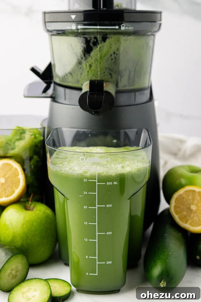 Freshly extracted cucumber juice in a glass positioned directly in front of a home juicer, emphasizing homemade goodness.