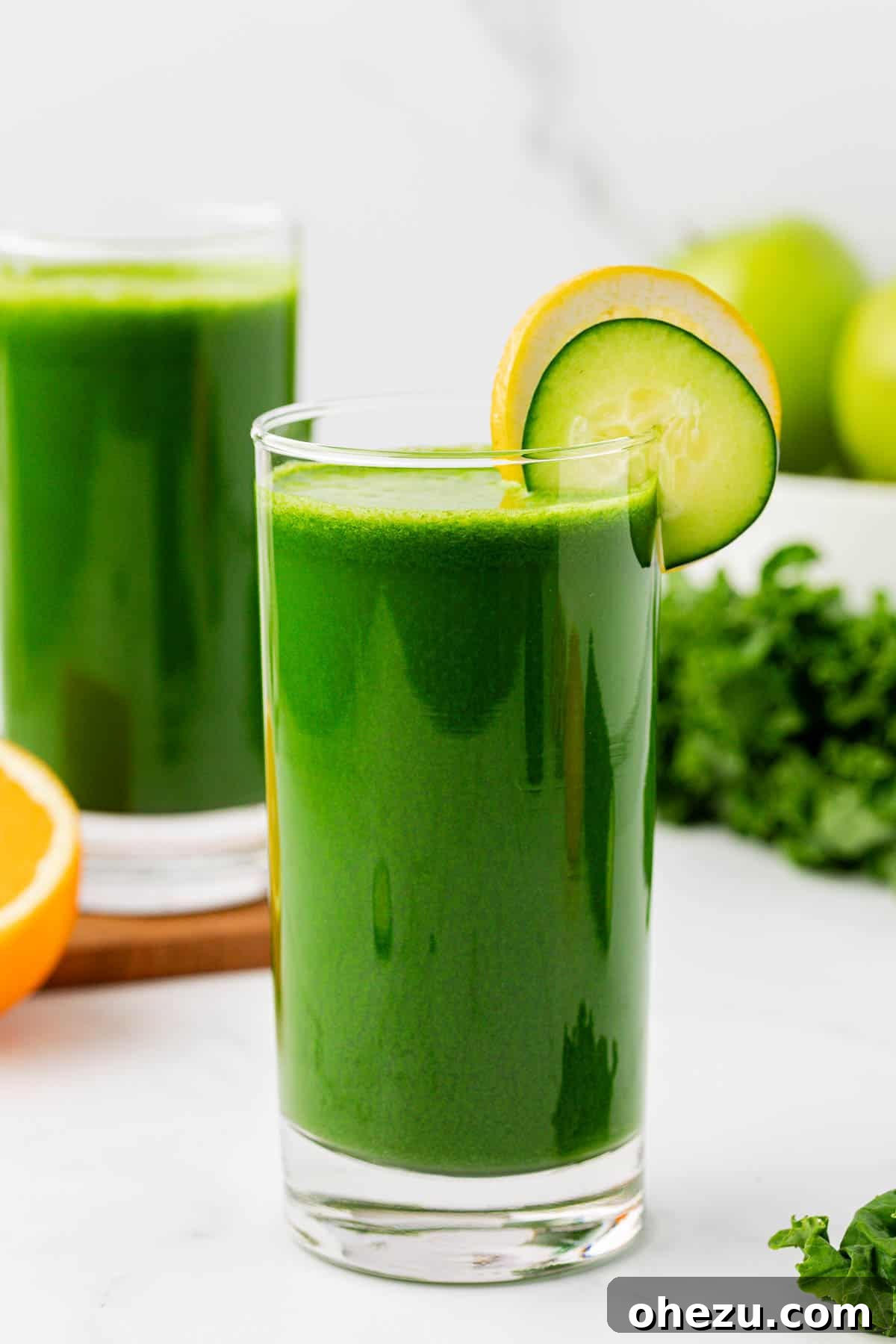 kale juice in a glass with a lemon and cucumber slice on the rim