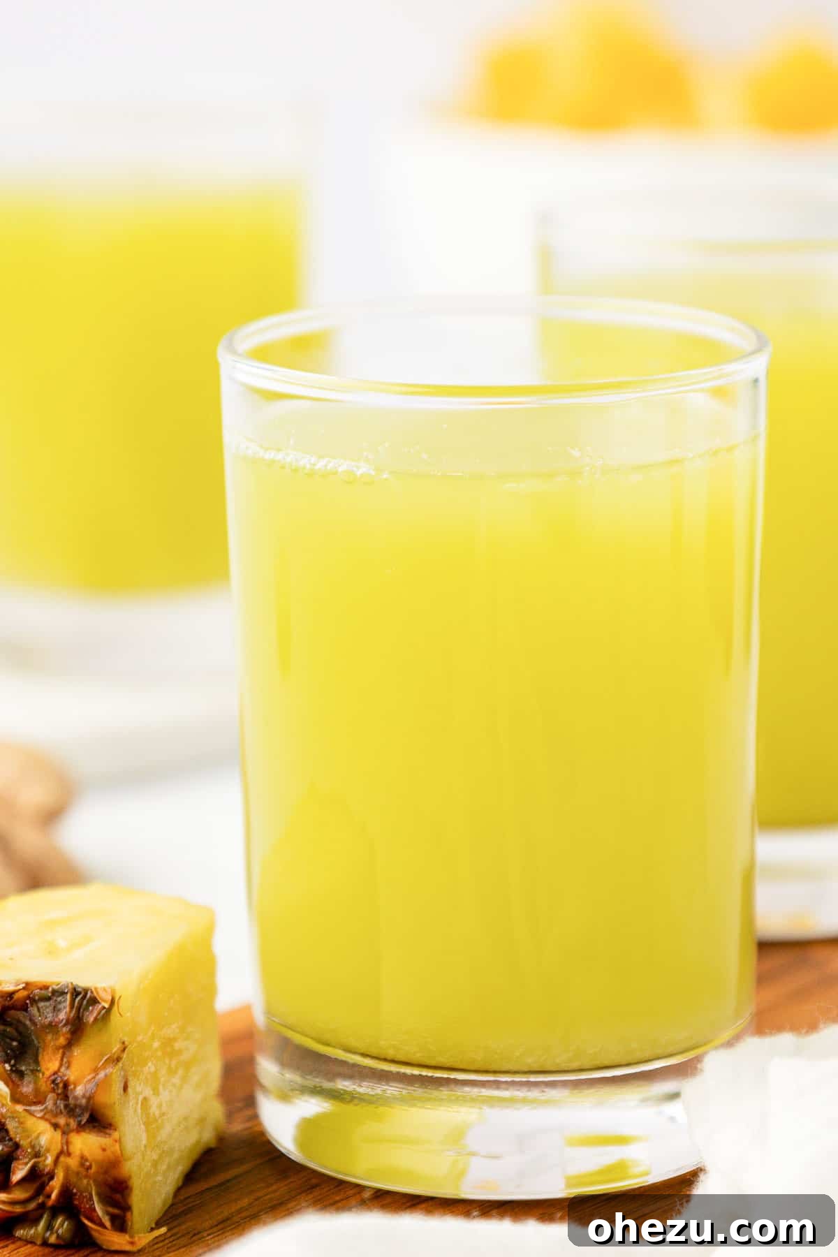 Glass of vibrant pineapple cucumber juice, garnished with a cucumber slice and a mint sprig