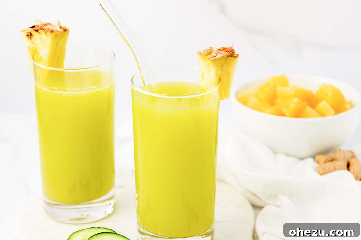 Two glasses of pineapple cucumber juice on a wooden tray, showing their vibrant green color