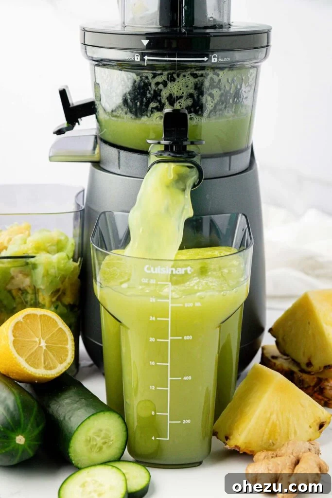 Fresh pineapple and cucumber chunks being fed into a juicer, with juice collecting below