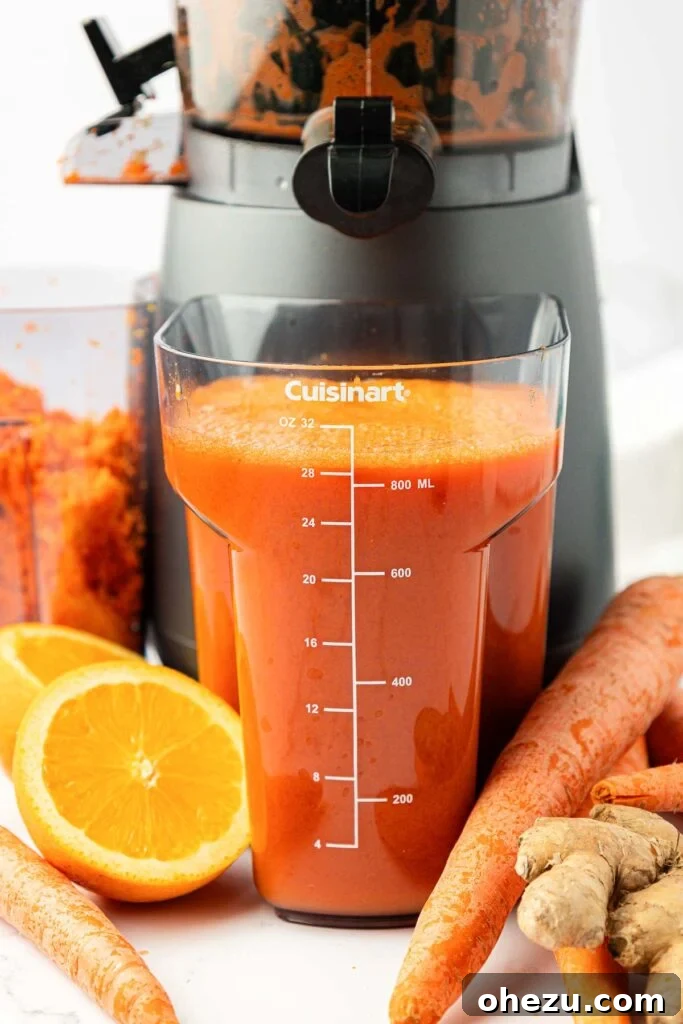 Freshly made carrot juice collected in a clear juicing canister or pitcher