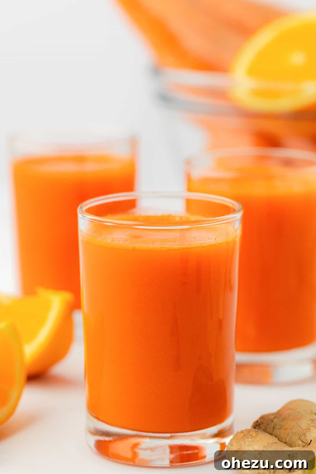 A beautiful glass of vibrant orange carrot juice resting on a rustic wooden table