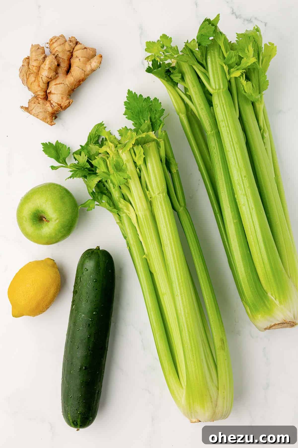 celery, cucumber, lemon, green apple, and ginger laid out for juicing