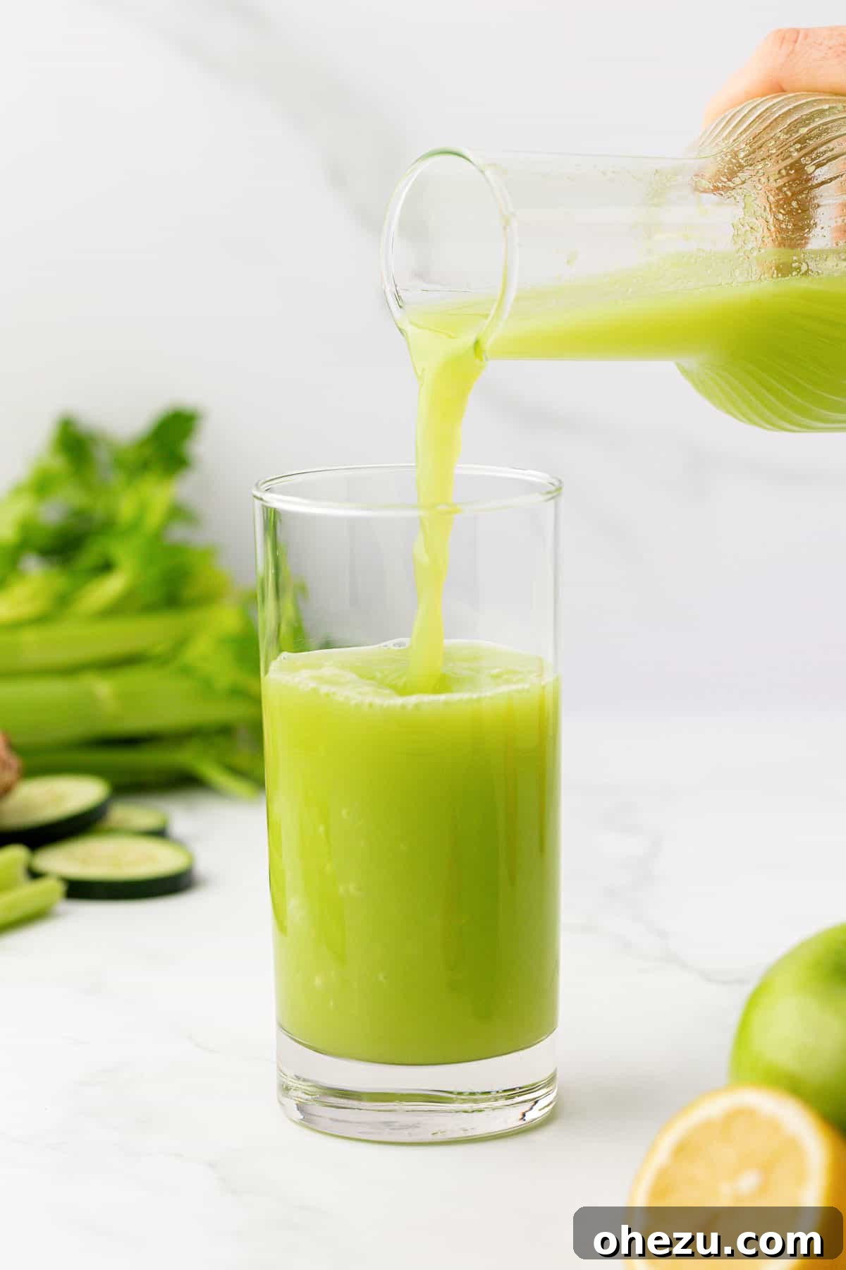pouring celery juice into a glass from a pitcher