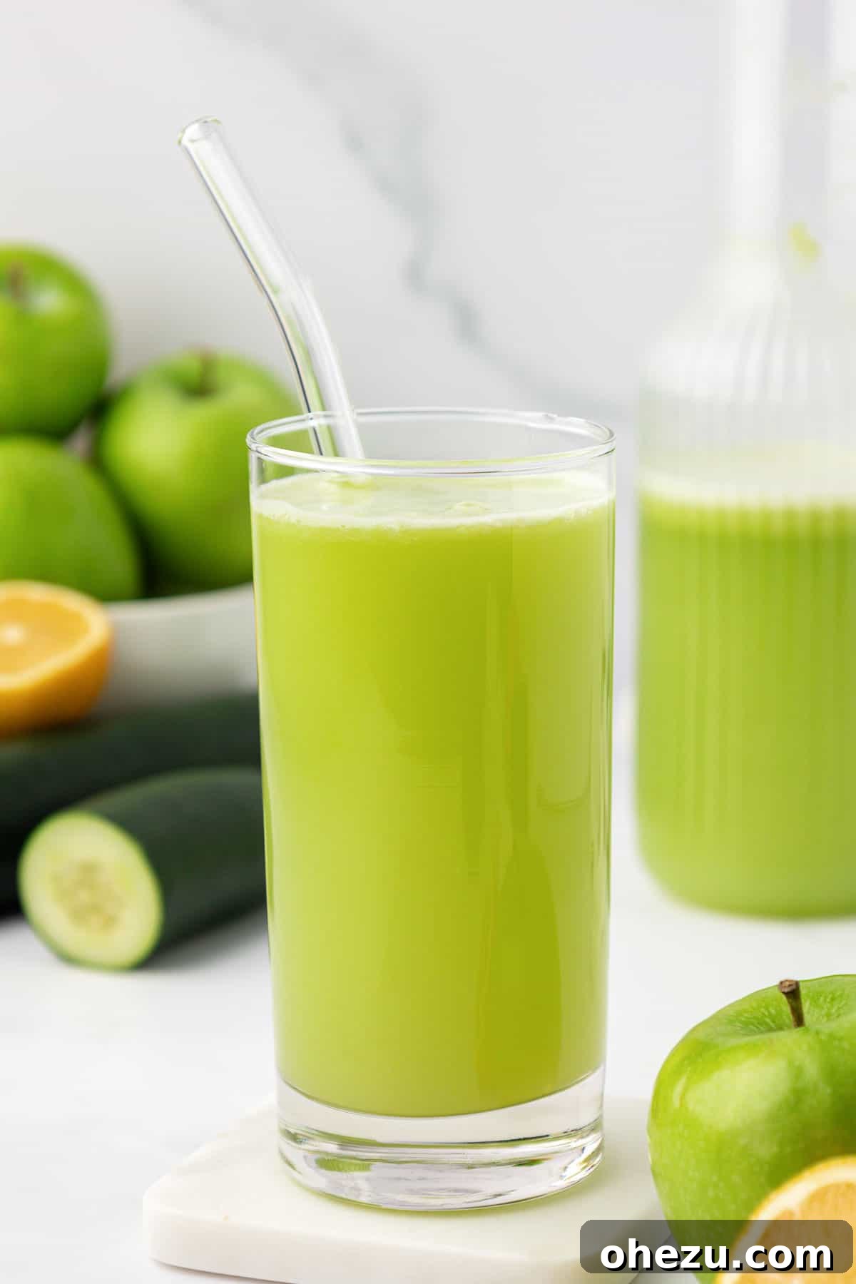 Green apple juice in a tall glass with a straw, inviting a refreshing sip