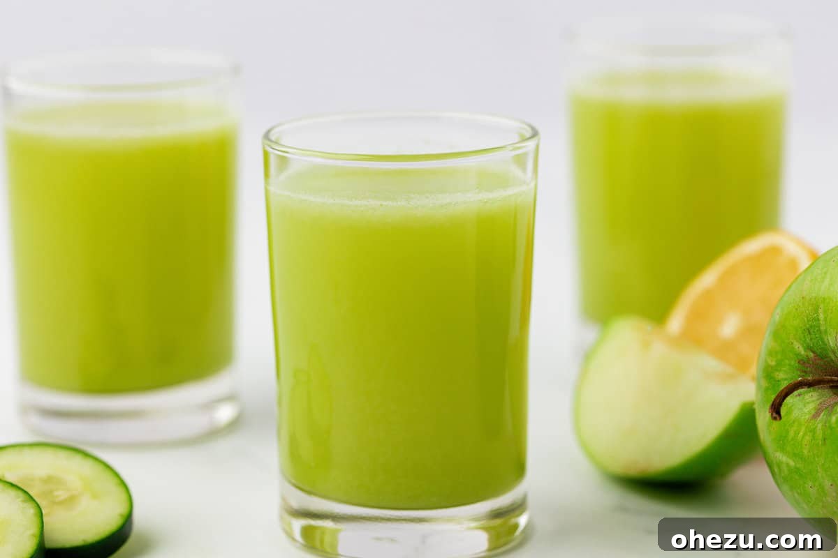 Two glasses of vibrant green apple juice side by side, on a wooden surface