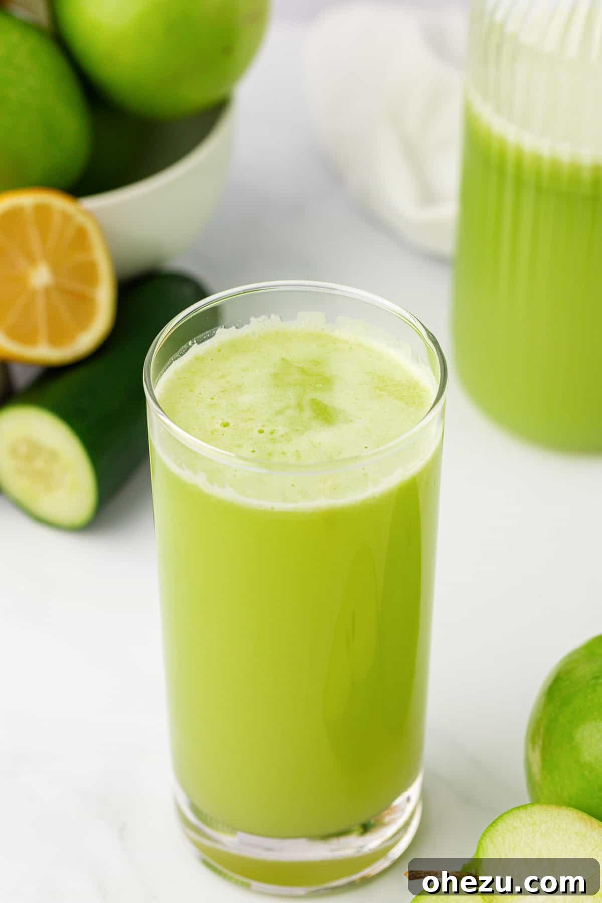 A tall, elegant glass filled with green apple juice, beautifully garnished