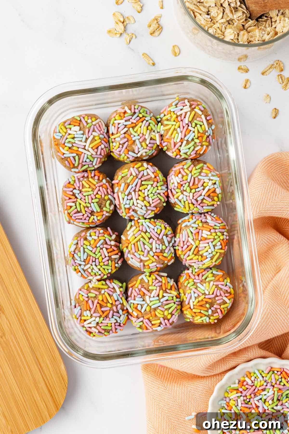 Close-up of three Birthday Cake Protein Balls, perfectly round and covered in colorful sprinkles, ready to eat.