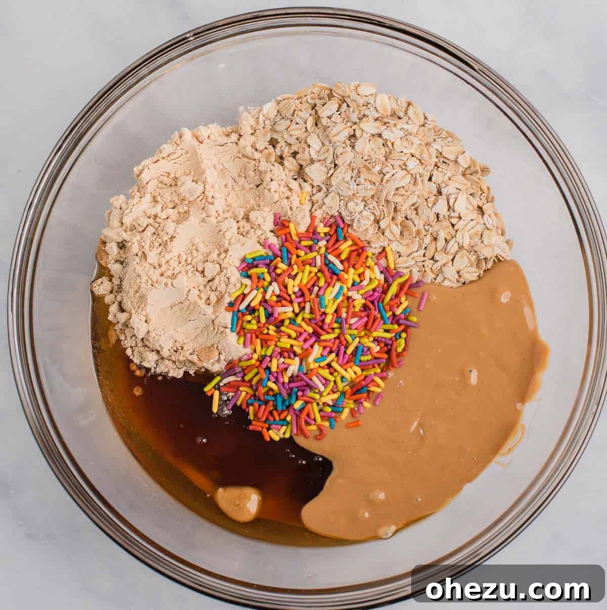 Close-up of protein ball ingredients, including oats, protein powder, and cashew butter, in a mixing bowl before combining.
