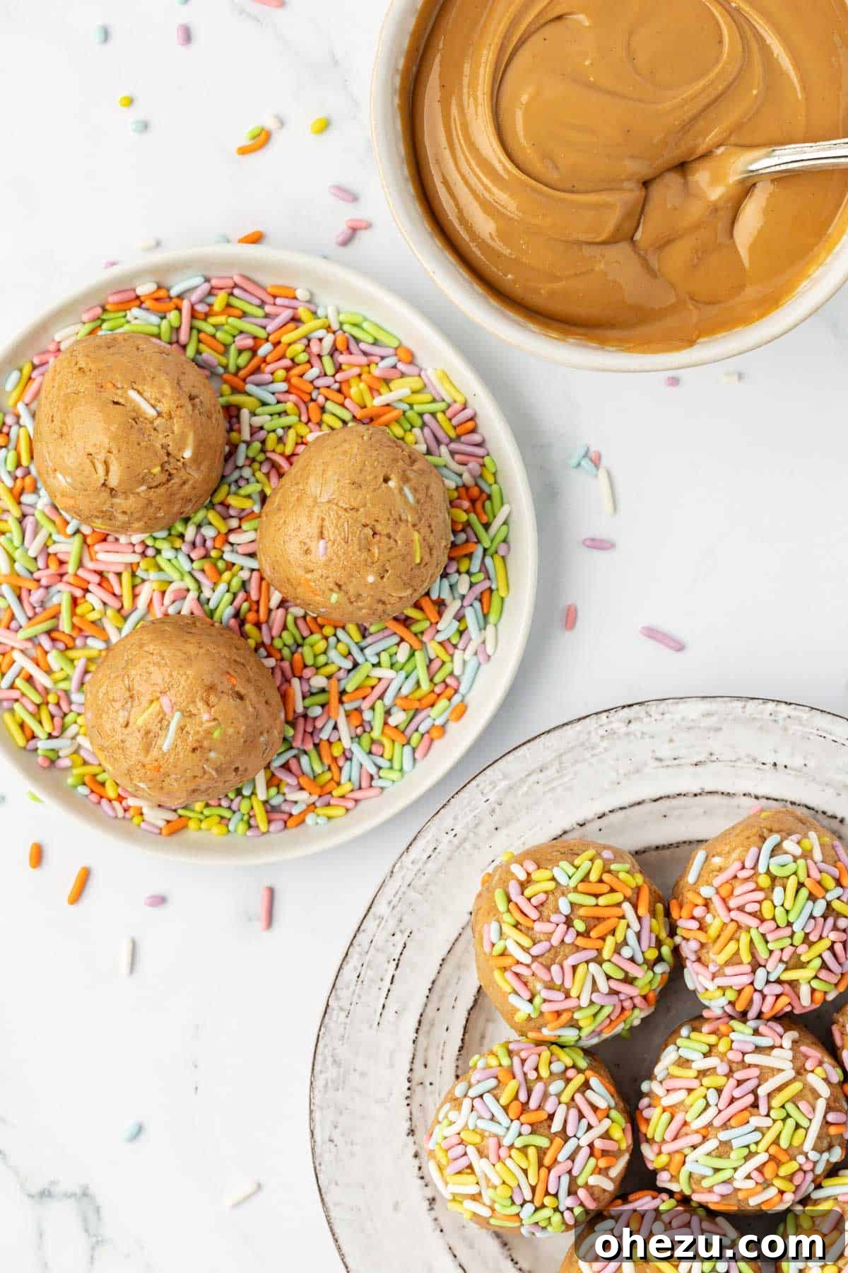 Hand scooping birthday cake protein ball batter onto a parchment-lined baking sheet.