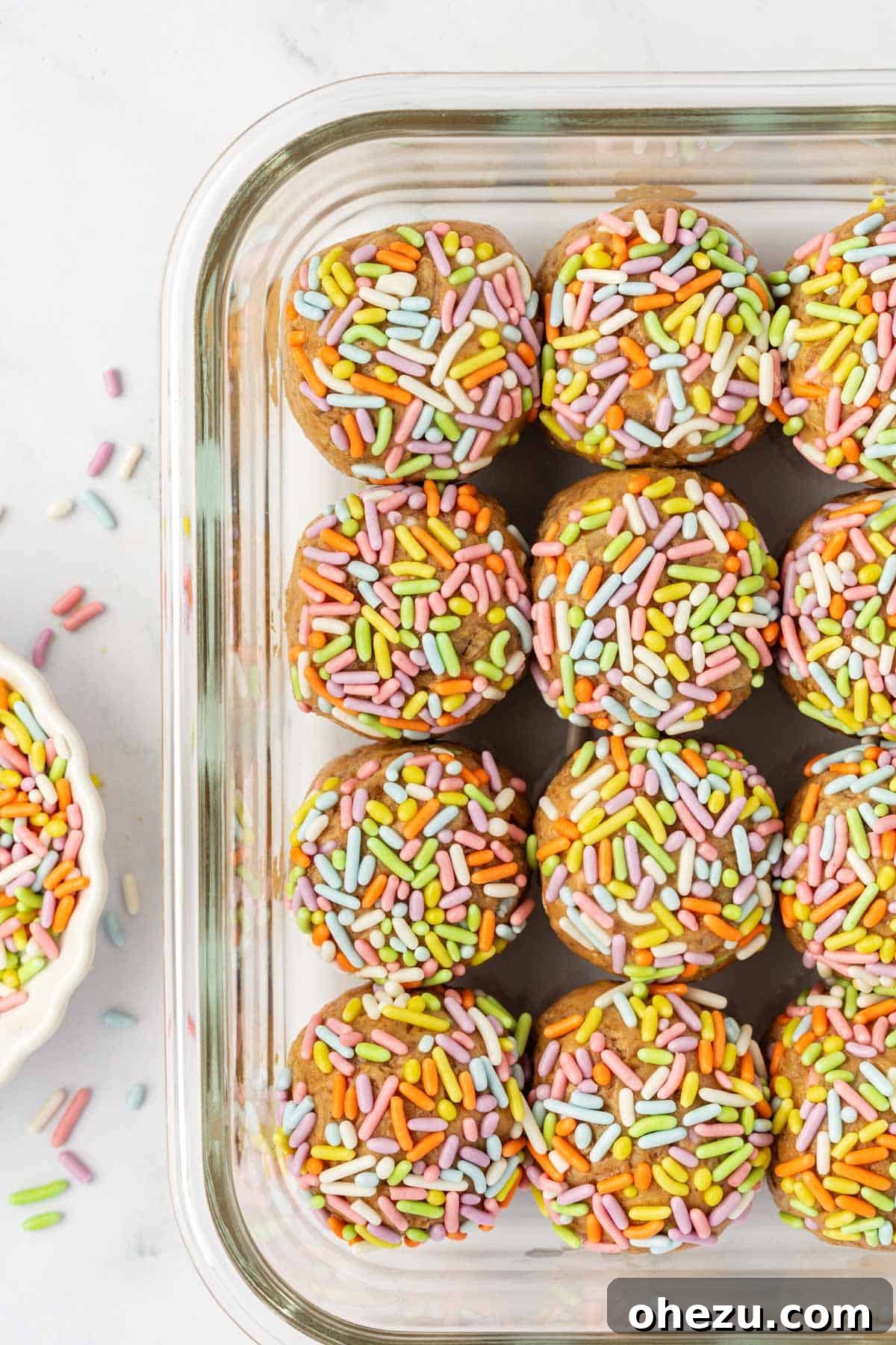 Finished Birthday Cake Protein Balls, coated in sprinkles and arranged on a parchment-lined baking sheet.