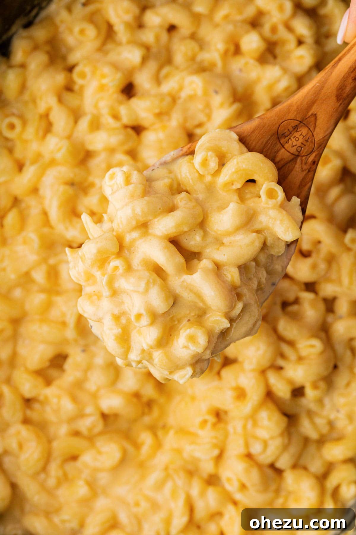 Creamy Slow Cooker Mac and Cheese 2 A wooden spoon scooping creamy mac and cheese from a slow cooker, highlighting its rich texture.