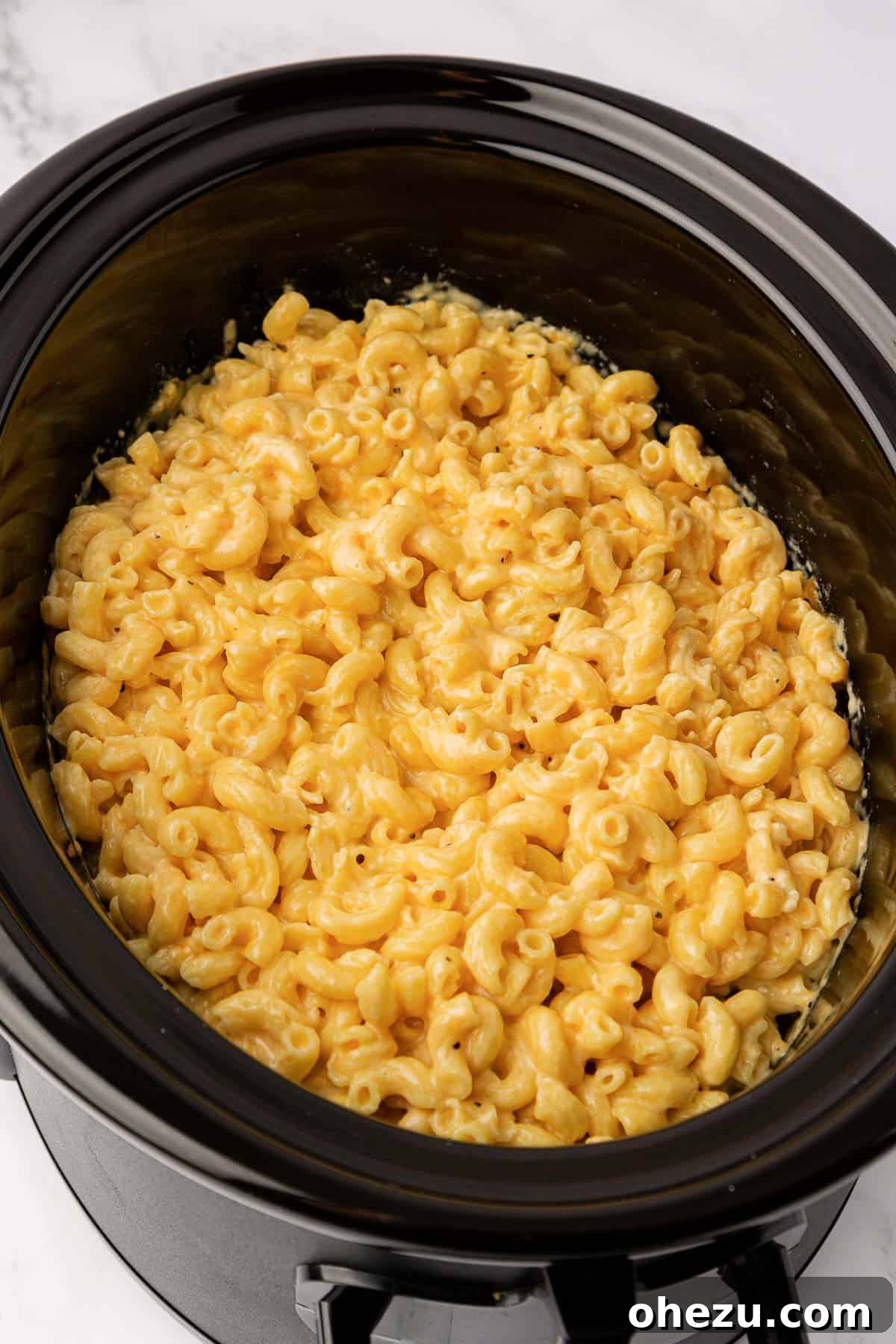 Creamy Slow Cooker Mac and Cheese 10 A close-up of mac and cheese bubbling gently in a crock pot, indicating it's nearly ready.