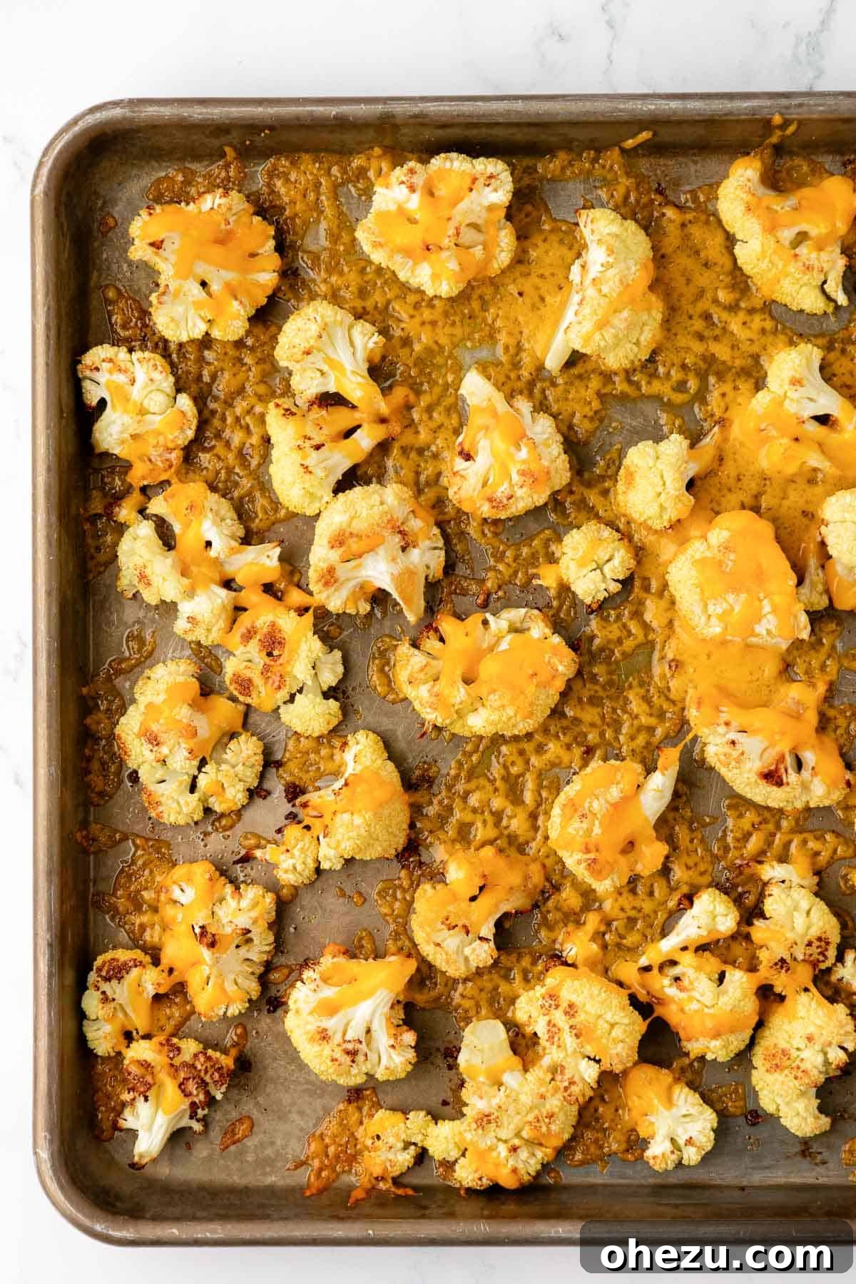 cheesy roasted cauliflower on a baking sheet, golden and bubbly