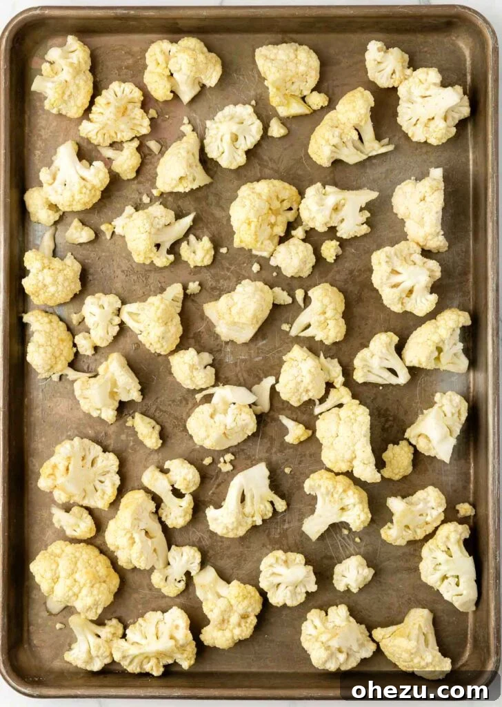 cauliflower florets spread evenly on a baking sheet before roasting